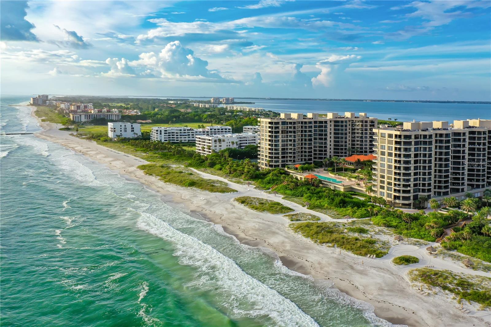 Welcome to The Water Club on Longboat Key, where refined Gulf-front living meets everyday comfort and effortless elegance. This ninth-floor residence delivers sweeping, unobstructed views from the Gulf of Mexico to Sarasota Bay. Spanning nearly 2,700 square feet, this three-bedroom (currently configured as two bedrooms plus den), three-bath home offers an ideal balance of indoor space and terrace access for those who crave the beach lifestyle without compromise. From the moment you step out of the private elevator lobby, you're met with clean architectural lines, serene tones, and expansive vistas through walls of floor-to-ceiling glass. The open-concept living and dining areas flow seamlessly from a granite-clad kitchen with crisp white cabinetry, custom tile backsplash, and island, creating a cohesive and functional space. The primary suite is its own private sanctuary—separated from the guest wing for ultimate privacy, it features three walk-in closets, a spa-style bath with soaking tub, glass shower, and a dedicated water closet. Step through sliding doors onto the primary’s dedicated Gulf-front terrace to soak in brilliant sunsets. Each guest bedroom includes its own terrace access and en-suite bath, ensuring comfort and privacy for visitors. The open den, located off the main living space, is ideally situated to serve as a flexible third bedroom, office, or media room. Ten-foot ceilings, crown molding, oversized tile and hardwood floors further elevate the interiors. A dedicated laundry room, wine storage, and secure, under-building parking add convenience and peace of mind. Residents at The Water Club enjoy a true resort-style living experience, with 24-hour staffed guard gate, impeccable concierge service, and a renovated beachfront clubhouse. Amenities include a social lounge, catering kitchen, state-of-the-art fitness center with spa services, four Har-Tru tennis courts, and a sprawling sun deck with heated pool and spa that overlooks the Gulf. Tucked along the pristine shoreline of Longboat Key, The Water Club offers an unmatched waterfront lifestyle with easy access to the island’s finest offerings. Enjoy nearby championship golf and marina amenities at the Longboat Key Club, explore the upscale shops and restaurants of St. Armands Circle, or take in the vibrant arts, dining, and cultural attractions of downtown Sarasota—just minutes away. Whether you're seeking a serene retreat or an active coastal lifestyle, this exceptional residence brings the best of Gulf-front living to your doorstep.