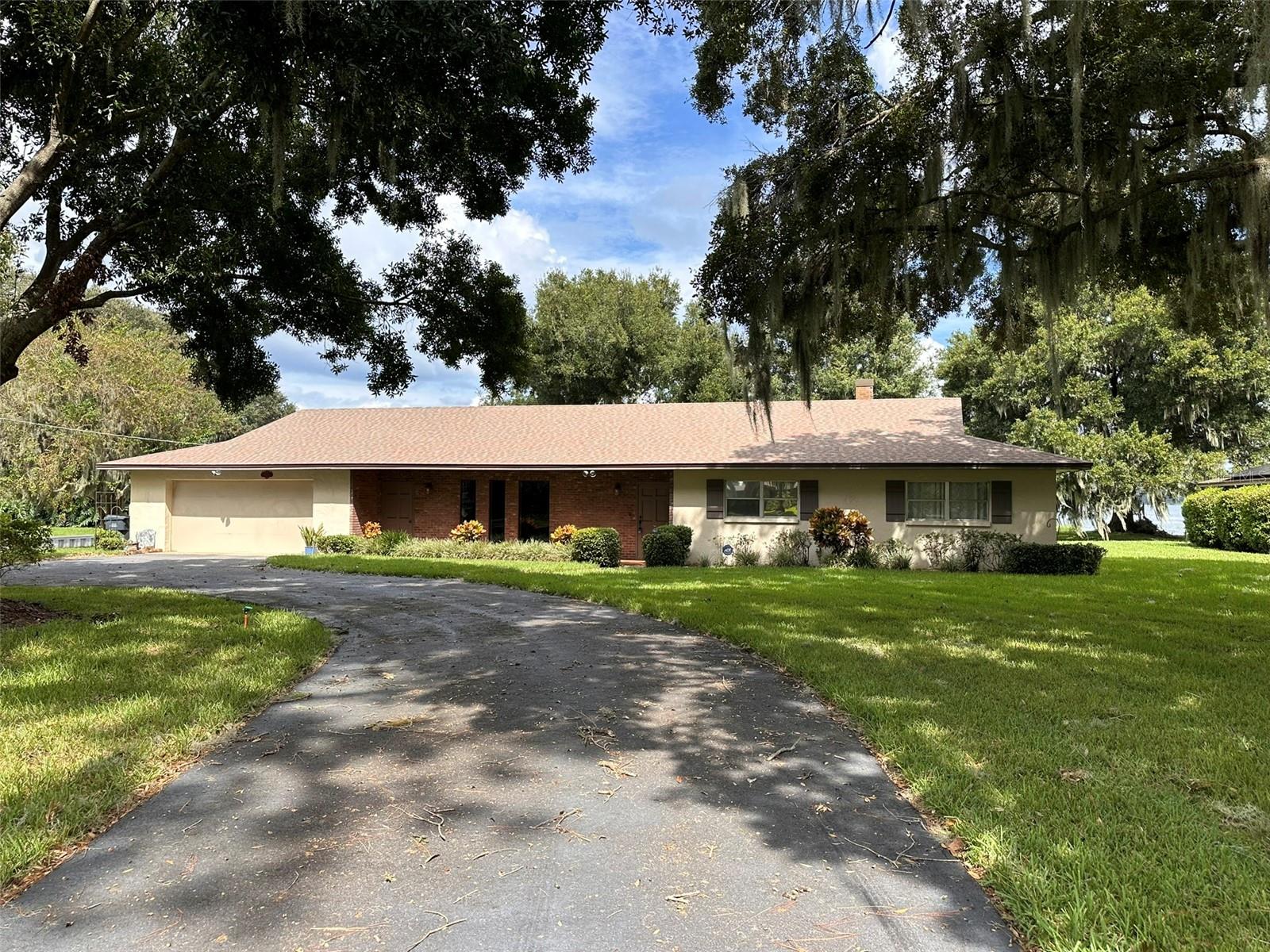 This stunning mid-century modern 2,640 sq ft lakefront rental offers direct access to the scenic Chain of Lakes, nestled between Lake Rochelle and the canal from Lake Conine. Located in a highly desirable community with no HOA restrictions, it’s a dream home for water enthusiasts and nature lovers alike.
With spacious rooms offering breathtaking lake views, this home includes key upgrades such as a whole-house water softener system and an updated kitchen. This home is on well and septic so there is no water bill! The property also features a lake-fed irrigation system, perfect for maintaining the lush 0.56-acre yard, while mature oak trees provide natural beauty and shade, enhancing the peaceful atmosphere.
The deep garage accommodates boat storage or multiple vehicles, complete with an outdoor shower, an additional bathroom, and a second shower inside the garage. Inside, four large bedrooms offer ample space for comfort and relaxation, making this lakefront retreat the perfect spot for renters seeking a peaceful and adventurous lifestyle with picturesque views. Call to schedule a showing today!