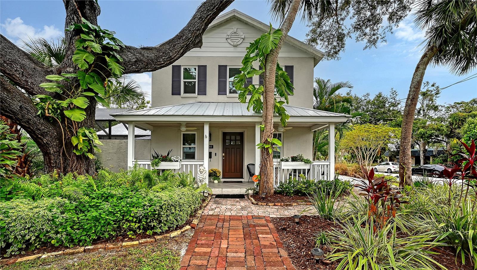 Perfectly situated in Sarasota’s vibrant Downtown within the coveted Gillespie Park neighborhood, this exquisitely renovated two-story Key West–inspired residence blends timeless architectural charm with modern sophistication. A magnificent oak tree graces the front yard, framing the home’s welcoming façade, while a historic brick driveway—crafted from original Sarasota street bricks—sets the stage for the artistry and attention to detail found throughout. Inside, solid wood floors, designer lighting, and refined finishes create a warm yet elegant ambiance. The gourmet kitchen impresses with custom cabinetry with soft-close drawers, quartz countertops, and top-tier appliances including a professional Forno gas range, seamlessly marrying function and style. Open-concept living and dining spaces are enhanced by an electric fireplace and abundant natural light streaming through windows and doors, many of which are impact-rated. Upstairs, rich hardwood flooring continues through the private quarters, including the serene primary suite featuring a custom-built walk-in closet and a spa-inspired bath adorned with porcelain tile, designer fixtures, and a soothing neutral palette. The flexible floor plan offers versatility for today’s lifestyles: a downstairs bonus area—currently used as a Pilates studio with private entry—is zoned for business or rental use and could easily serve as a family room, media room, primary/guest bedroom or fitness space. A beautifully appointed 600-square-foot apartment offers full independent living, complete with a contemporary kitchen, induction cooktop, full-size washer and dryer, and a spacious private balcony—ideal for guests, extended family, or short-term rental income (one-week minimum rental permitted). Additional highlights include a temperature-controlled wine room, an oversized laundry area with attic storage, three zoned HVAC, and a security system. Outside, a lush courtyard with screened lanai and heated pool creates a tranquil retreat for relaxing or entertaining amid tropical landscaping. Set on a spacious, fenced corner lot, the property offers abundant privacy along with an expanded 2½-car garage featuring an impact-rated door and generous storage. Residents of Gillespie Park enjoy one of downtown Sarasota’s most walkable locations—just moments from fine dining, boutique shopping, arts and cultural venues, SRQ International airport, and the scenic Bayfront. The neighborhood’s namesake park offers tennis and pickleball courts, dog areas, and a lively community spirit that captures the essence of urban Sarasota living. Blending the character of Sarasota’s historic past with the ease of modern luxury, this exceptional residence delivers rare flexibility, craftsmanship, and an enviable location in the heart of it all.