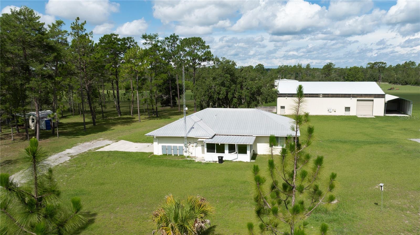One or more photo(s) has been virtually staged. Nestled in the Wings Field subdivision of Morriston, this 25-acre estate with Airstrip access offers a unique blend of tranquility, functionality, and freedom for aviation enthusiasts, outdoor lovers, or those seeking space and privacy. This 3-bedroom, 2-bath single-family home features an open-concept layout with a combined living and dining area, a spacious enclosed Florida room, and 1,276 sq ft of heated living space. Built in 2009 with a durable metal roof, central air, and thoughtful design, it’s move-in ready and full of possibilities. The property is designed for both comfort and utility with a 2-car garage, RV carport, boat parking, shed with carport, and an airplane hangar complete with a barn apartment—featuring a bedroom, small kitchenette and full bath with a walk-in shower. All tools and equipment in the hangar are included to convey with the sale. The land features planted pines and beautiful timber, offering natural beauty and long-term investment potential. Energy efficiency is also a plus, thanks to the solar power system with two ground-mounted arrays and a total of 22 panels—10 powering the main home and 12 powering the hangar. Enjoy privacy, open skies, and the freedom of a private airstrip, all while being conveniently located near Williston and Ocala.