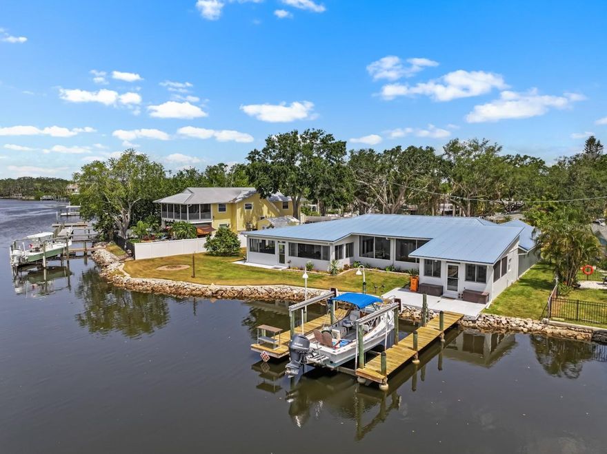 This WATERFRONT paradise is the perfect oasis for a boating/fishing enthusiast, or simply anyone dreaming of a coastal cottage getaway! Brand new front doors and front porch tile! OPEN WOOD DOCK with 10,000-lb BOAT LIFT, FULLY FENCED at the end of a dead-end street with privacy gate, plenty of parking space, and NO HOA or CDD, so bring your boat, trailer, RV, ATVs, and other toys! NEW is the word used over and over when describing this beautiful 3-bedroom, 3-bathroom, 2-car garage home: NEW HVAC (2025), NEW PLANTATION SHUTTERS throughout, NEW hot water heater (2024), all major appliances are NEW (2024), and NEW PAINT inside and out! From WOOD CEILINGS to CROWN MOLDING, there are so many special touches to this relaxing refuge. The METAL ROOF includes hurricane strapping that was inspected this year (2025). The spacious COVERED & SCREENED FRONT PORCH is surrounded by fresh, colorful landscaping and has two fans for breezy comfort year-round. Step through the glass double-door entry to be met with TILE FLOORING throughout! There's a 7X12 storage room off the living room, and a GREAT ROOM with even greater windows to let in that gorgeous water and conservation view, and they're all equipped with blinds for shielding the light and warmth when desired. The immaculately UPDATED KITCHEN features a BREAKFAST BAR, ISLAND, STAINLESS STEEL APPLIANCES, and sliders to the back lanai. The Primary Suite includes blackout curtains, a 6X10 WALK-IN CLOSET with CUSTOM BUILD-INS, and an EN-SUITE BATHROOM with a DUAL SINK VANITY, a WALK-IN SHOWER with DUAL SHOWER HEADS, a separate JETTED TUB, and a water closet. The Primary Bedroom also provides access to the enclosed FLORIDA ROOM - install a hot tub, set up seating, or since it leads right on out to the dock and boat lift, continue using this space as a fishing room! The front bedroom has its own EN-SUITE BATHROOM featuring a single sink vanity and shower stall, and the third bedroom (currently used as a craft room) includes TWO CLOSETS! The interior laundry room includes cabinetry, counterspace, a storage closet as well as a coat closet by the garage, its own sink, LG washer/dryer, and connects to the third full bathroom with its single sink vanity and shower stall. The COVERED & SCREENED WRAP-AROUND LANAI was TILED in 2023 and has NEW CEILING FANS, and there's a perfect covered grilling spot off to the side. This home is truly something special. Feel like you've escaped the rest of the world and start making new memories here.