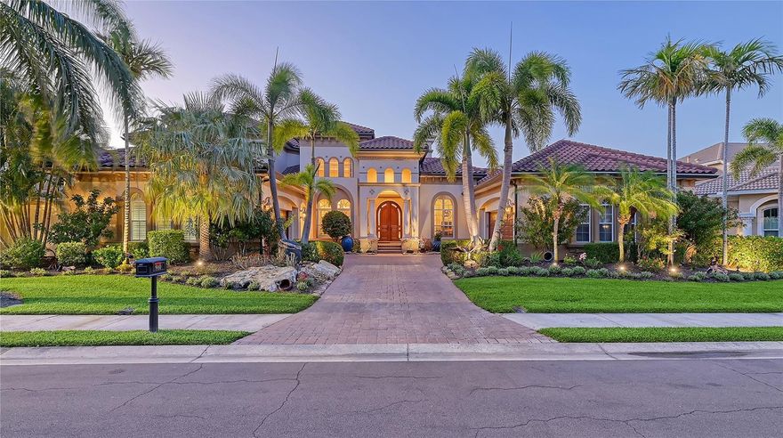 Nestled within the exclusive gated confines of the Island at Riviera Dunes, this luxury residence stands as a testament to elegance and opulence. Situated along a hurricane shelter basin with deep water dockage and an oversized dock primed for a yacht, the home beckons to those who appreciate the finer things in life.
Upon crossing the threshold, one is immediately ensnared by the allure of an infinity pool, a shimmering oasis enveloped by cascading waterfalls crafted by the skilled hands of Lucas Pools. This aquatic masterpiece seamlessly merges with the surrounding basin, offering breathtaking vistas that permeate nearly every corner of the main living areas.
The interior exudes sophistication, boasting exquisite woodwork, tray ceilings, and masterfully crafted cherry floors adorned with oak inlays, including a resplendent compass rose in the foyer. The living and dining spaces flow effortlessly, accentuated by a magnificent marble mantel fireplace that serves as the focal point of the room. 
A butler's pantry and wine closet flank the entrance to the kitchen, where culinary delights await. Equipped with a spacious working counter, a suite of Wolf appliances, Subzero refrigerator with additional freezer drawers, and dual dishwashers, this culinary haven is a chef's dream. The kitchen and family room provide an open and inviting space for relaxation with family and friends. Adorning the family room, a wall of sliders stands as a gateway to the outdoor oasis, inviting guests to step outside and indulge in the splendor of the stunning pool patio. With a gentle push, these expansive glass panels effortlessly disappear, seamlessly merging the interior with the exterior, blurring the boundaries between indoor luxury and outdoor serenity. Throughout the stunning patio ceilings adorned with star lights further enhance the ambiance of tropical splendor, complementing the mesmerizing allure of the Lucas Pool and its cascading waterfalls.A full kitchen and gas fireplace, are perfect for alfresco entertaining under the starlit sky.
The master ensuite is a sanctuary unto itself, offering panoramic views of the pool and water, a cozy fireplace, and a lavish master bath complete with a soaking tub, oversized shower, and a charming private outdoor shower enveloped by a gentle cascade of water. Also, on the first floor one will find a spacious office, and two additional bedrooms sharing a well-appointed bath. 
Ascending via the elevator to the second floor reveals an expansive great room with a kitchenette, wrapped in a second-story patio that affords even more breathtaking water views. Two additional bedrooms, one of which doubles as an office, and a bath complete the upper level, offering a retreat from the world below.
From its unparalleled waterfront location to its lavish amenities and meticulous attention to detail, this residence stands as a testament to luxurious island living at its finest.