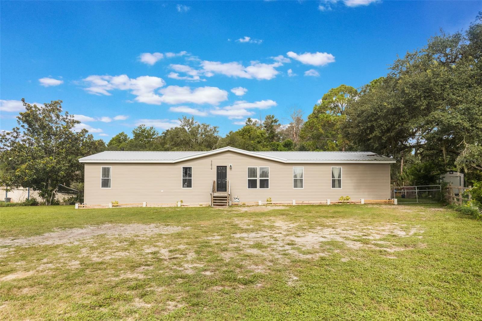 Welcome to this beautifully updated double-wide manufactured home sitting on a ½ acre of high and dry, fully fenced land in Eustis, Florida! Offering the perfect mix of modern upgrades and country charm, this property is ideal for those looking for space, comfort, and room for animals.
Inside, you’ll find 2,128 square feet of living space featuring 4 spacious bedrooms and 2 full baths. The oversized primary suite is a true retreat with a massive walk-in closet and an additional flex space, perfect for a home office, nursery, or private sitting area.
The home was completely updated in 2021 with top-quality improvements, including a 50-year metal roof, brand new well, updated septic system, and all-new interior finishes—giving you peace of mind for years to come.
Step outside and enjoy the freedom of country living. The property is fully fenced, making it perfect for goats, chickens, horses, or any animals you’d love to bring along. A barn in the backyard is ready for use, offering endless possibilities for storage, hobbies, or livestock.
Whether you’re looking for a homestead, a family retreat, or simply a home with plenty of space both inside and out, this Eustis property checks all the boxes!