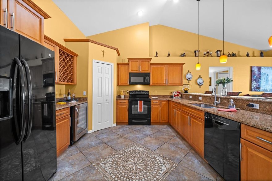 This bright and cheerful, 3-bedroom den pool home has great curb appeal, a new roof (2024), and is not in a flood zone! Upon approach, the home says “welcome”! The upgraded kitchen in this 1,800 +/- SF gem is perfectly positioned steps from the dining room and the living area. It boasts granite counters, quality wood cabinetry topped with decorative molding, double sinks, sleek black appliances including a double-door refrigerator with an icemaker, a wine refrigerator, and a built-in wine rack. There is additional counter space perfect for your personal coffee bar or an array of handy kitchen appliances. A raised counter easily accommodates bar-style seating for four. A large pantry? Of course. Your dining room offers LVT flooring, and windows facing south, allowing the Florida sunshine to shine in. The living area is quite spacious and easily accommodates larger furniture or even sectional furniture and a big screen TV. The living-area-to-kitchen-flow is perfect for entertaining or a comfortable, relaxing evening at home. You will enjoy and appreciate the quality, decorative tile-on-the-diagonal throughout the main living areas. No carpet here. The spacious great room design offers excellent flow and showcases lovely views of the sparkling pool, the extended lanai, and the fully fenced (wood) backyard oasis with mature low maintenance landscaping. This tropical retreat provides privacy, a shaded space for outdoor dining, and areas for sunbathing. The den, with French doors and LVT flooring, is ideal for a quiet home office, a craft room, or a cozy reading area. The split floor plan ensures privacy with an oversized primary suite, large enough for a king bedroom suite and a sitting area. The sleek, modern, primary bath will impress even the savvy buyer with extensive, decorative wall tile, dual vessel sinks, contemporary countertops, a very, private - private water closet, and a luxurious walk-in shower with multiple shower heads. The additional two guest rooms also offer LVT flooring and share the tub/shower combo guest bath. Your indoor laundry room has newer appliances, shelving, and room for cabinetry. This priced to sell Cape Coral pool home has it all!