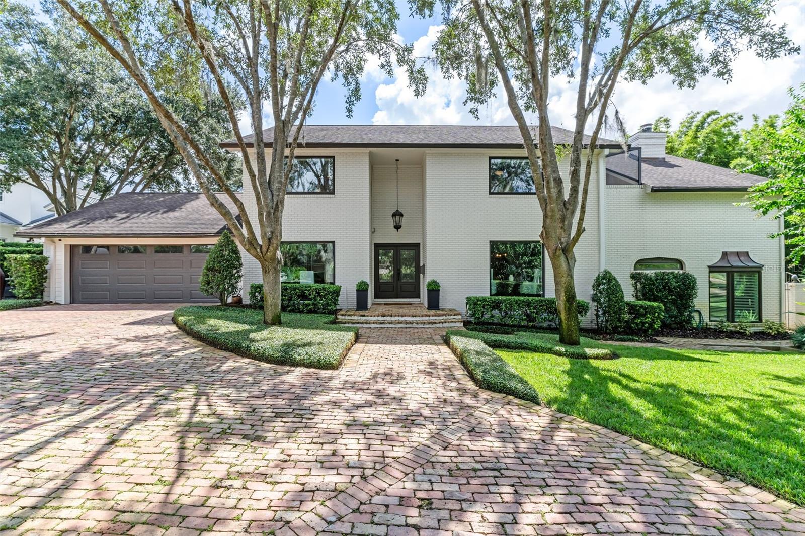 Tucked away on a quiet cul-de-sac lined with multi-million-dollar estates, this Winter Park residence offers an enviable blend of privacy, lifestyle, and location. Less than a mile from Park Avenue, the Winter Park 9 Golf Course, and the Racquet Club, this address puts you at the center of the city’s most coveted amenities. A deeded greenbelt easement to Lake Osceola—just 100 yards from the front door—provides effortless access for boating, kayaking, or paddle boarding on the Winter Park Chain of Lakes.
The two-story brick home spans 4,328sf with 4 bedrooms, 4 baths, and a 2-car garage. Inside, character and craftsmanship shine with brick archways, custom millwork, tongue-and-groove ceilings, and two wood-burning fireplaces. The gourmet kitchen features Thermador appliances, marble counters, and a walnut-topped island, while the expansive primary suite boasts a private screened patio, a fully built-out oversized walk-in closet, and a spa-like bath. Two bonus rooms upstairs provide flexible space for work or play, while updated systems—including a 2018 roof, three HVAC units, dual-pane windows, updated drainage, whole house generator, mosquito misting system, whole house alarm, and smart home upgrades—ensure comfort and peace of mind.
Equally impressive are the grounds. The front garden is graced with jasmine, mature oaks, and manicured plantings, while a Chicago brick horseshoe driveway easily accommodates six or more cars. Out back, a private retreat unfolds with a lagoon-style saltwater pool and spa surrounded by flagstone decking, a summer kitchen, covered patio with fans and lighting, and a dedicated pool bath.
Living here is about more than a home—it’s about lifestyle. With gardens and stunning architecture at every turn, culture, shopping, and dining just minutes away, and lake access at your fingertips, this property offers a rare opportunity to experience the very best of Winter Park.