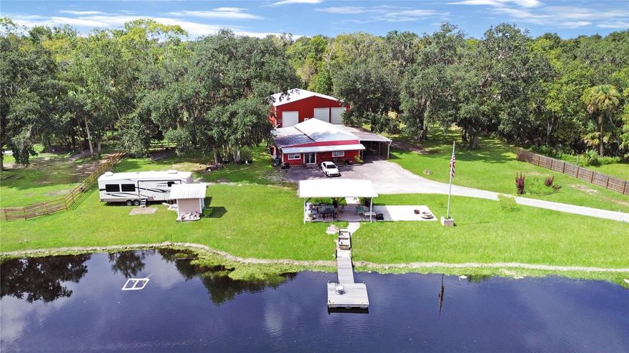 Looking for space, privacy, and freedom — all within minutes of the beach? This rare 5.7-acre ranch east of I-95 in New Smyrna Beach is the perfect blend of peaceful country living and unbeatable location. With four parcels sold together and agricultural zoning, this property offers endless possibilities for animal lovers, hobbyists, small business owners, or anyone craving wide-open space near the coast. There are two impressive buildings designed for versatility and function. The front building has a little bit of everything — a dedicated office, a cozy 1-bedroom apartment with shared kitchen and bath, a special dog grooming room, a large barn-style garage with loft, and a covered carport currently used for tractor and feed storage. There’s even an air-conditioned dog house — because everyone deserves comfort here! The second building (built in 2022) is a dream workspace — 3,600 square feet with spray foam insulation, 16’ high sidewalls, and three roll-up doors (two 14’, one 12’). Outfitted with 110v and 220v outlets along every wall, it’s ideal for large equipment, car projects, RV or boat storage, or any creative pursuit. Upstairs, there’s a nearly finished office ready for your final touches, while downstairs offers an unfinished area perfect for a paint station or wood shop. Outdoors, the property truly shines. It’s fully fenced and cross-fenced with both 4-board and wire fencing, multiple pastures with water and shade, and RV parking with 30-amp service. Enjoy gatherings by the small lake, complete with a floating dock, fountain, pavilion, covered patio, open seating area, and fire pit — the ultimate spot to unwind and take in the Florida sunsets. Whether you’re looking for a private retreat, equestrian setup, hobby farm, or place to run your business from home, this New Smyrna Beach property has it all — space, flexibility, and an unbeatable location just minutes from the sand, shops, and dining. Only 1-mile to Tractor Supply, 2-miles to Publix, 3-miles to I-95 or Canal Street and 5-miles to Flagler Avenue and the beach!  Come see this truly rare find — you won’t find another like it east of I-95 in New Smyrna Beach! All measurements are approximate.