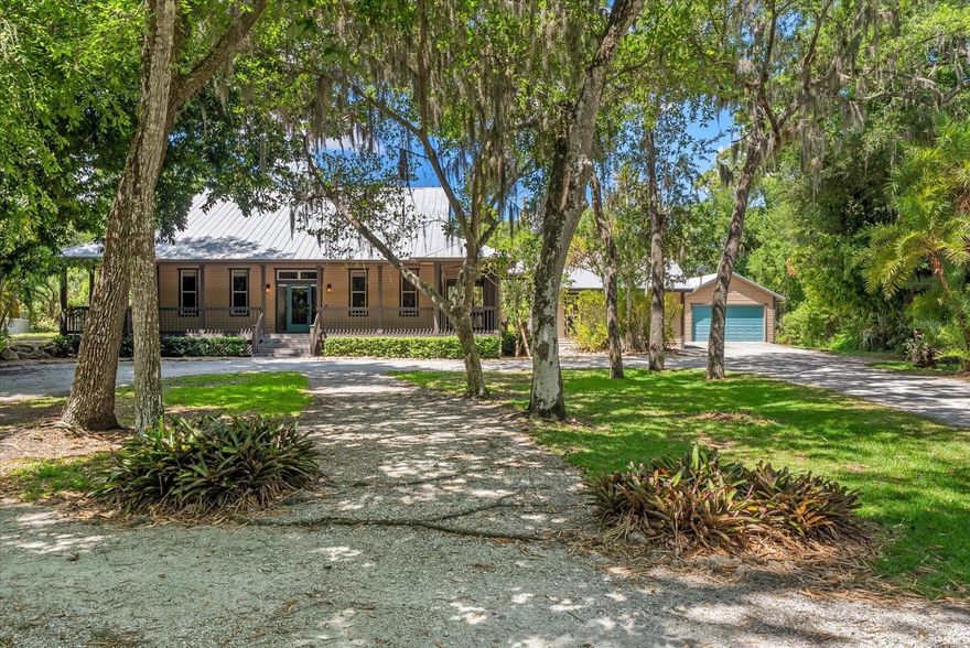 Tucked away at the end of a quiet dead-end street on 1.3 lushly landscaped acres, this private Sarasota retreat feels worlds away from the ordinary. Blending farmhouse warmth with the character and comfort of a mountain lodge, 1165 Vereda Verde is a rare hidden gem offering exceptional privacy, flexible living spaces, and a setting designed for both relaxation and entertaining.
Surrounded by mature trees and natural greenery with virtually no neighboring homes in sight, the property creates a peaceful compound-like atmosphere rarely found this close to the heart of Sarasota. A large wrap around covered porch welcomes you inside where rich hardwood flooring, soaring pine plank cathedral ceilings, shiplap accents, and dramatic stone fireplaces create a warm and inviting feel throughout the home. 
The open living and dining areas flow seamlessly into a spacious entertainer’s kitchen featuring granite countertops, stainless steel appliances, wood cabinetry, center island seating, built in desk area, and generous storage. The owner’s suite offers its own private retreat with soaring ceilings, fireplace, French doors opening to the lanai, walk-in closet, and a beautifully updated bath with soaking tub and walk in shower. 
Outdoor living is where this property truly shines. The covered and screened lanai overlooks a sparkling heated saltwater pool and spa with oversized sun shelf and expansive paver decking, creating an ideal setting for entertaining, family gatherings, or simply enjoying the peaceful surroundings in complete privacy. 
Adding even more versatility is the detached bonus space complete with soaring pine plank ceilings, multiple French doors, and endless possibilities as a media room, gym, art studio, office, recreation space, or creative retreat. An oversized detached garage and abundant room for boats, RVs, recreational vehicles, or hobbies further enhance the property’s flexibility. 
With no HOA or flood zone restrictions and a surprisingly central Sarasota location west of the interstate and just minutes to University Town Center, dining, shopping, Nathan Benderson Park, and I-75, this is a property that offers the rare combination of privacy, character, land, and convenience all in one.