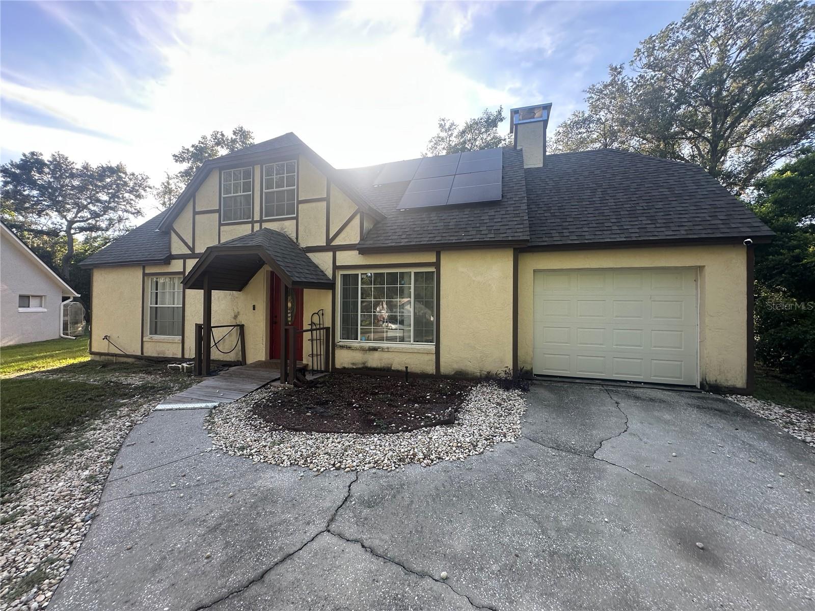 Discover this unique Tudor Styled two-story home nestled in a quiet cul-de-sac just a short walk from historic downtown Mount Dora! Featuring 4 spacious bedrooms and 2 full baths, this home offers a warm and inviting layout with wood laminate flooring throughout.
The primary suite is a large yet cozy retreat with a fireplace, vaulted wood ceilings, a window seat, and a walk-in closet. The formal dining room boasts elegant wainscoting and opens to the back patio through beautiful French doors—perfect for entertaining. The kitchen features classic oak cabinetry.
Enjoy the outdoors in a large, fenced backyard shaded by mature oak trees. There is an above ground pool area and deck that is ready for your personal improvements. This home is move-in ready and full of character.