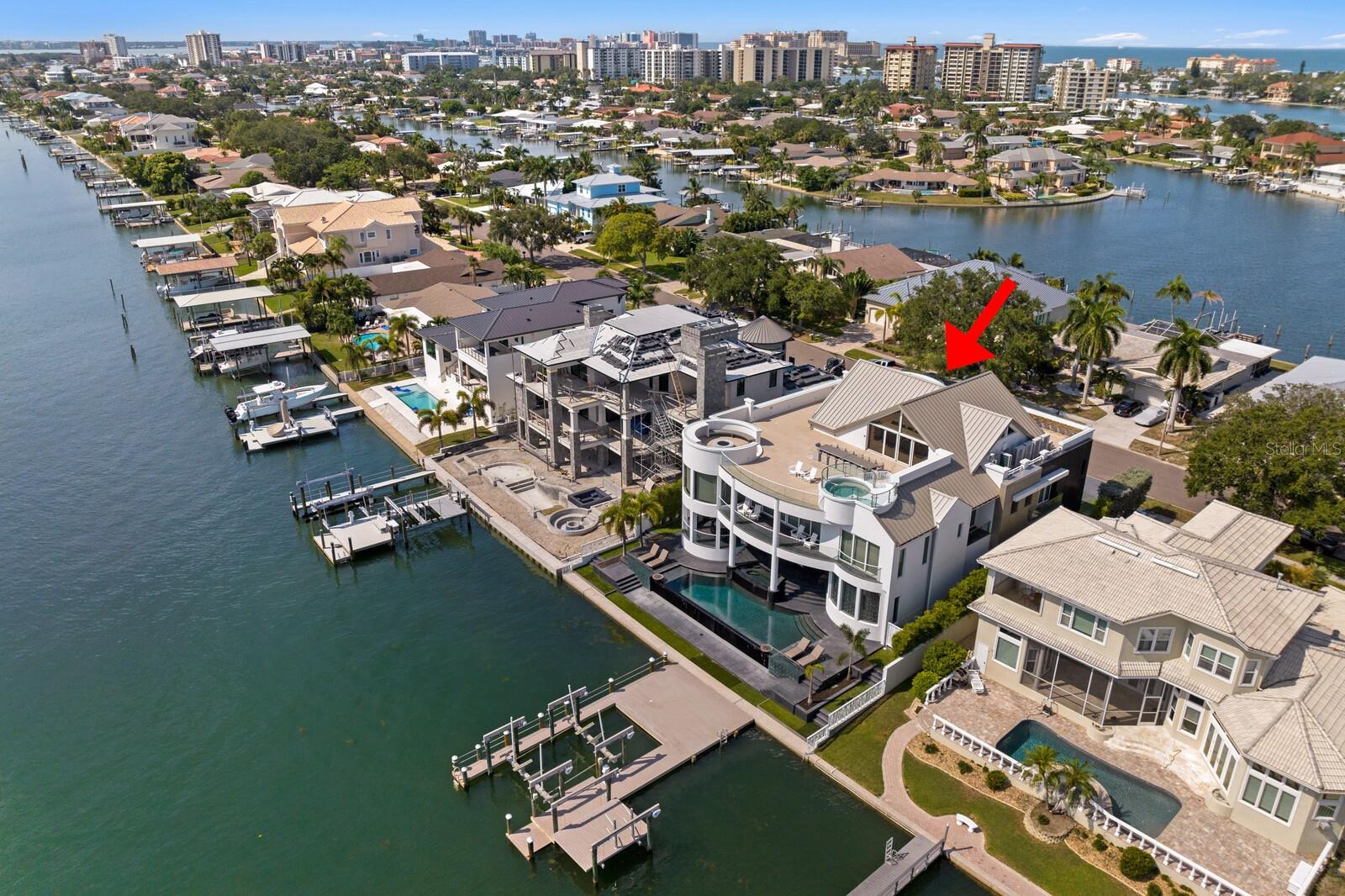 Located between Clearwater Beach and downtown Clearwater, immerse yourself in this indulgent Island Lifestyle in Island Estates. Refined coastal modern architecture boasts breathtaking views and elevated design elements throughout over 11,500 of total square feet in this highly-desired enclave. Make every day feel like a vacation excursion with a home that seamlessly blends the indoors out to resort-style entertaining areas, delivers an immersive audio and video experience, while being enveloped in spectacular views and sunsets beyond compare. Decadent design elements and a dramatic clear rail curved stairway welcome you to glamorous living spaces that includes 5 bedrooms, 5 full and 3 half baths and 8,548 SF, premier statement lighting and floor-to-ceiling windows. A design aesthetic embraces the concave window placement and fluid circular appointments from seating areas to the ceiling architectural features. A state-of-the-art chef’s kitchen with Sub-Zero Wolf and Meile appliances provides such fluid appointments in the center island and seating area that overlook the living room with custom window treatments and full retracting doors that lead the expansive covered waterfront entertaining terrace. There is an adjacent family room with linear fireplace and entertaining bar also on the main level. Additional refined areas include a full theatre experience media room, dual offices, and elevator. Four ensuite guest bedrooms await upstairs, along with the private primary suite oasis that features a sitting room, spectacular water views and magnificent bathroom offing a soaking tub and premier steam shower. The masterpiece moments continue to the luxurious outdoor living areas that deliver nothing short of extraordinary, with expansive terraces, clear terrace railing, numerous entertaining and gathering areas, along with an infinity pool, fire features. An elevator leads you to the coveted rooftop terrace lounge with elevated spa, firepit, dining area and wet bar. A private deep water composite dock features water, electrical, 30K lift, plus jet ski lifts for endless recreation, boating and more in this outstanding location. Additional appointments include all NEW advanced HVAC/Humidity System, Hurricane Resistant Engineering, Creston Home Automation system, impact windows, A/V Security, central vacuum, NEW roof and a 4-car garage. Less than a mile from award-winning Clearwater Beach, enjoy access to outstanding beaches, shopping, dining and entertainment, along with boating access to the Gulf from this luxury oasis.