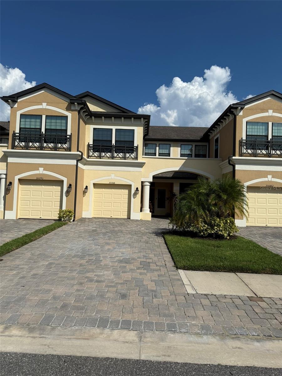 Welcome to this charming townhome located in the gated community of Windermere Estates, right in the heart of Wesley Chapel! Enjoy the convenience of being just minutes from top-rated schools, community College, Wiregrass Mall, and Hospital. This home features an open-concept layout with a modern kitchen showcasing 42" cabinets with crown molding, sleek stone countertops, stainless steel appliances, and a large island with breakfast bar seating—perfect for entertaining. The first floor is finished with durable ceramic tile throughout and offers a spacious screened-in lanai for relaxing evenings. Upstairs, you’ll find a large master suite with a generous walk-in closet, along with two additional bedrooms and a full bath. Lawn care, water and trash are all included—providing you with a truly maintenance-free lifestyle. Whether you're a first-time homebuyer or an investor, this gorgeous townhome is a fantastic opportunity!
