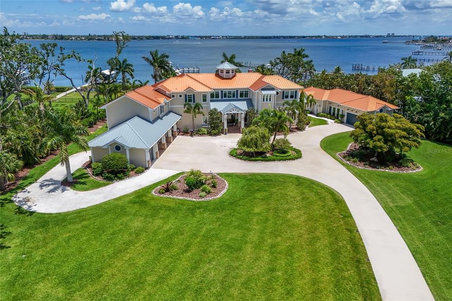 Introducing “VISTA DEL FIUME”, an ABSOLUTELY SPECTACULAR GATED MANATEE RIVER ESTATE situated on nearly 3 ACRES with deep water access and breathtaking panoramic views! Truly one of the most impressive private waterfront residences ever offered on the Manatee River!!! Tucked behind private gates and surrounded by impeccably manicured grounds, towering palms, lush tropical landscaping, expansive lawn space, private pond with fountain, and a full sport court, this extraordinary estate offers the ultimate blend of luxury, privacy, boating lifestyle, and resort style living. A long winding driveway leads to the stunning coastal inspired residence featuring Hardy Board siding, standing seam metal roof, Chicago brick accents, and over 7,000 sqft of meticulously crafted living space with 6 bedrooms, 6.5 bathrooms, and 6 covered parking spaces including a 5 car garage and porte cochere. Step through the grand front porch entry into a breathtaking great room where soaring ceilings, dramatic transom windows, custom millwork, and walls of glass perfectly frame the incredible river views while flooding the home with natural light. The open concept design seamlessly blends the great room, dining area, and kitchen into one extraordinary waterfront entertaining space. The chef’s kitchen is remarkable featuring dual oversized islands, separate refrigerator and freezer, Thermador 6 burner gas range with griddle, double dishwashers, farmhouse sink, prep sink, walk in pantry, custom two tone cabinetry, exposed wood beams, pendant lighting, and a charming sitting room overlooking the pool and river. Additional main level spaces include a private office, mudroom, elevator access, powder bath, incredible wine grotto with extensive storage, and a spectacular bonus/game room complete with full bar area, mini fridge, keg system, ice maker, sink, and accordion serving window opening directly to the outdoor entertaining areas. The luxurious primary suite is a true retreat featuring a private balcony overlooking the river, spa inspired bathroom with soaking tub and oversized walk in shower, dual vanities, and massive custom closets. Upstairs also includes three additional ensuite bedrooms, secondary laundry room, and dramatic hallways overlooking the great room and waterfront beyond. Above the garage you will find a beautifully finished mother in law suite, while a detached structure creates a true waterfront compound feel featuring an additional guest suite, full air conditioned gym, and tackle room. The home also features three laundry areas and surround sound throughout. The outdoor living experience rivals any private resort with multiple covered entertaining areas, brick flooring, roll down screens, outdoor kitchen, multiple dining and lounge spaces, gorgeous pool and spa overlooking the water, and a stunning firepit area positioned directly along the riverfront. Boaters will appreciate the exceptional composite dock with 9 foot wide walkway easily accommodating a golf cart, deep water access capable of accommodating large yachts and sailboats, and three lifts including 10,000 lb, 13,000 lb, and 30,000 lb lifts. Enjoy unforgettable sunsets, endless outdoor entertaining, and one of the most breathtaking waterfront settings on Florida’s Gulf Coast. This is a once in a lifetime opportunity to own one of the finest luxury waterfront estates on the West Coast of Florida!