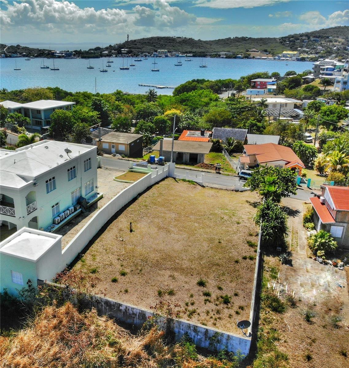 This property is located on the outskirts of town, within walking distance (0.3 miles) of local eateries, laundromat, and boat storage facilities. The terrein is sloped, offering views of the island's Harbor Ensenada Honda. The property is fenced by a concrete wall with an entrance gate, for privacy.