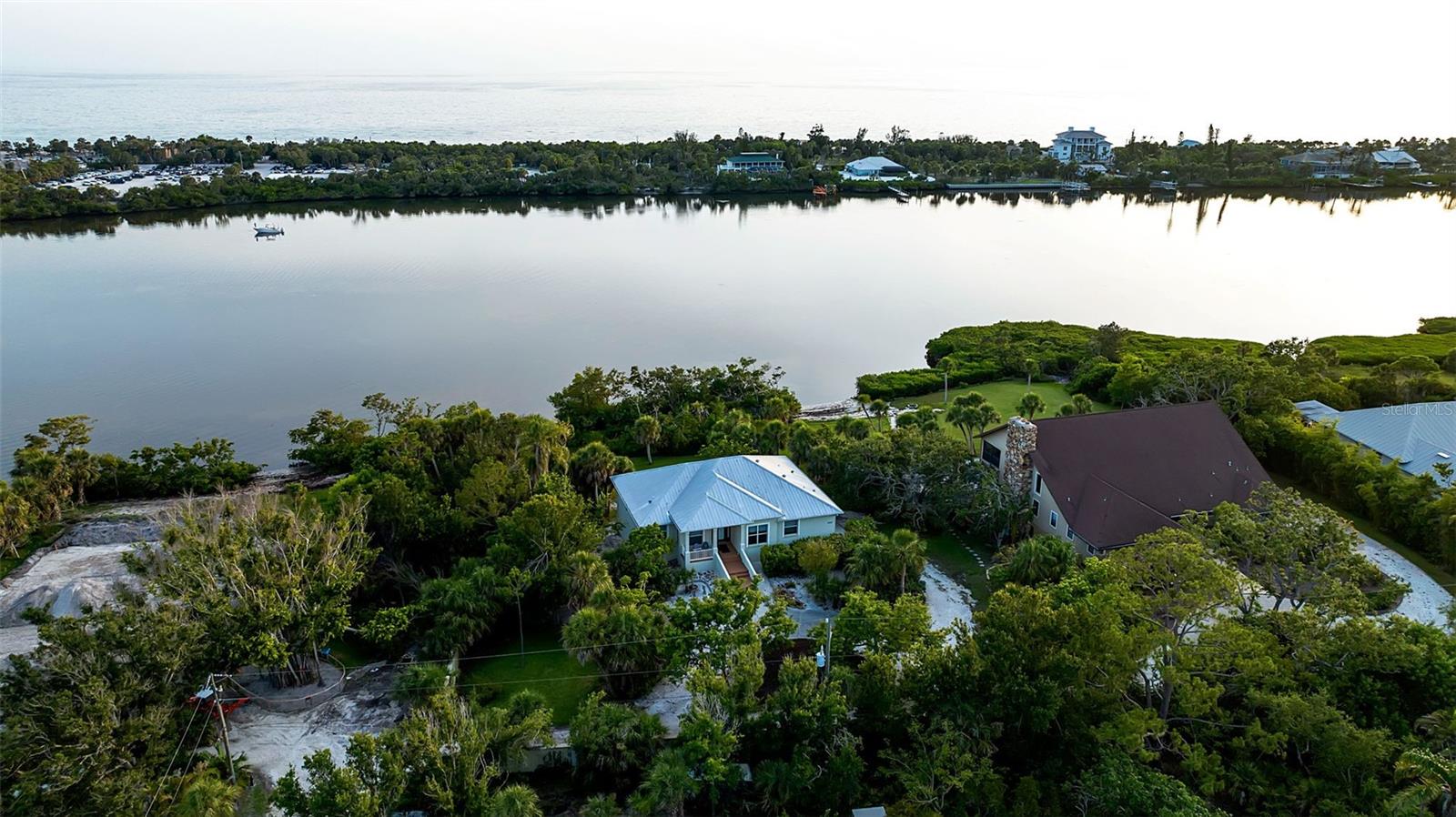 Your Florida waterfront dream awaits on Lemon Bay! Picture yourself waking up to breathtaking expansive water views in this stunning elevated home with 151 feet of pristine water frontage. Imagine sipping your morning coffee on the expansive screened lanai as dolphins play in the bay and manatees glide by below, then taking an afternoon stroll to world-renowned Manasota Beach less than a mile from your door. This 3-bedroom, 2-bath sanctuary built by Peter Shipps offers 2,043 sq. ft of elegant living space where you'll entertain guests in your spacious kitchen featuring premium Fulgor Milano Fridge, Bosch dishwasher, and gorgeous Corian countertops . Retreat to your luxurious master suite with dual sinks, walk-in shower, and custom built-ins, or host overnight visitors in the separate guest wing with its own private entrance. The real magic happens on your 0.75-acre waterfront paradise where you'll spend endless hours watching spectacular sunsets, observing abundant wildlife from your screened sanctuary, and living the coastal lifestyle you've always envisioned. With an additional 2,000 sq ft of blank canvas space below, you can create your own boat storage, workshop, entertainment area, art studio, or whatever your heart desires. Protected by hurricane-rated windows and a durable metal roof, your waterfront haven is ready for you to add floating and/or fishing docks to complete your personal slice of paradise in one of Florida's most coveted coastal communities!