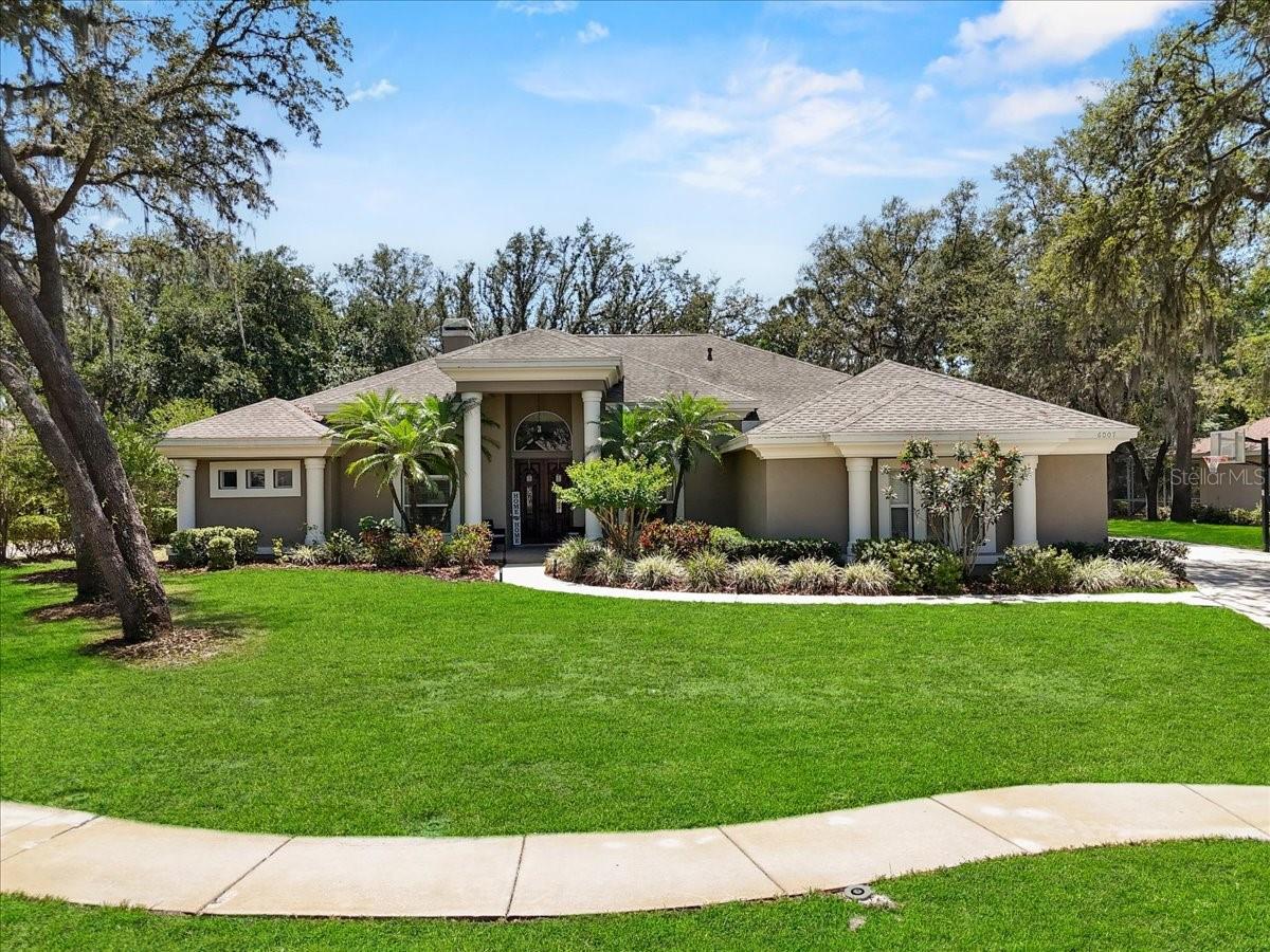 *Seller is offering $10,000 towards Rate Buydown and/or Closing Costs!!* Welcome to 6007 Hammock Hill Ave located in the desirable gated community of FishHawk Trails. This exceptional property offers the perfect blend of comfort, style, and functionality. Featuring a true in-law suite with its own private entrance and full kitchen, this home is ideal for multi-generational living or guest accommodations. Inside you’ll find thoughtfully designed spaces with recent upgrades including three brand new AC units. This stunning 5-bedroom, 4-bathroom home boasts over 4,800 square feet of living space and features an open concept floor plan that is perfect for entertaining. The kitchen is a chefs dream with a huge island, quartz countertops, subway tile backsplash, custom cabinets, a pot filler, large farmhouse sink, wine fridge, and a walk in pantry with sliding barn doors. The breakfast nook features mitered glass windows overlooking the pool. The family room has triple glass pocket sliders that open to the lanai. The dining room overlooks the mature landscaped front yard. The inviting living room showcases a fireplace with custom built-ins and a triple sliding door to the pool. French doors lead you into the bright office complete with a closet. The large master suite overlooks the pool and has a sitting area with a door that leads to the lanai. The en-suite offers two walk in closets, double vanities, a frameless walk in shower and a beautiful soaking tub. The secondary bedrooms are spacious and one bedroom features a private bathroom. Crown moulding throughout. The large lanai has a covered sitting area and covered bar area, a heated pool and spa with overflow jets and plenty of space for large gatherings.
The roof is 6 years old. Plenty of room to play in the fenced in, tree shaded, oversized back yard that also includes a fire pit. This home sits on .45 acres near the end of a cul-de-sac and has great curb appeal with a 3 car side entry garage, oversized driveway, and small basketball court. The 24 hour gated community of FishHawk Trails has miles of nature trails, a 285-acre nature preserve, baseball and soccer fields, tennis courts, pickle ball courts, and 2 playgrounds. NO CDD! Don’t miss out on the chance to make this beautiful property your own, schedule a showing today!