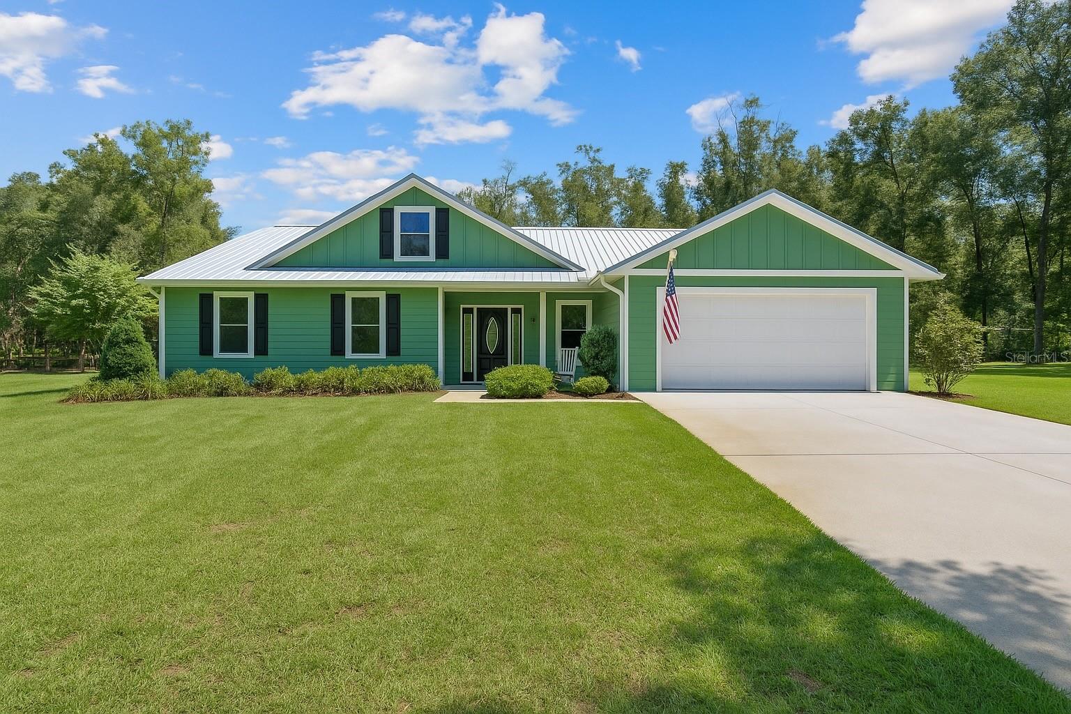 Discover country living at its finest with this beautifully maintained 5-acre property in Chesbourough's Corner! The inviting front porch leads you inside to an open-concept layout. The kitchen seamlessly connects to the living and dining areas and features quartz countertops, a large island, stainless steel Samsung appliances, a Frigidaire built-in oven and microwave, electric range, and pantry. Just off the dining room, you’ll find a versatile additional living space with a half bath and direct access to the garage. The spacious primary suite has an ensuite bath with dual vanities, a walk-in shower, and a linen closet. Two additional bedrooms offer plenty of room, while the interior laundry room with utility sink provides everyday convenience. Step outside to a 10x20 back patio, ideal for relaxing or entertaining. On the west side of the property, a 24x40 detached garage with lean-to (approx. 22x14) adds extra functionality. Built with quality in mind, the home offers a stem wall foundation, energy-efficient spray foam insulation in the attic, and the convenience of underground utilities. Enjoy no HOA, and a prime location less than 10 minutes from Ginnie Springs!