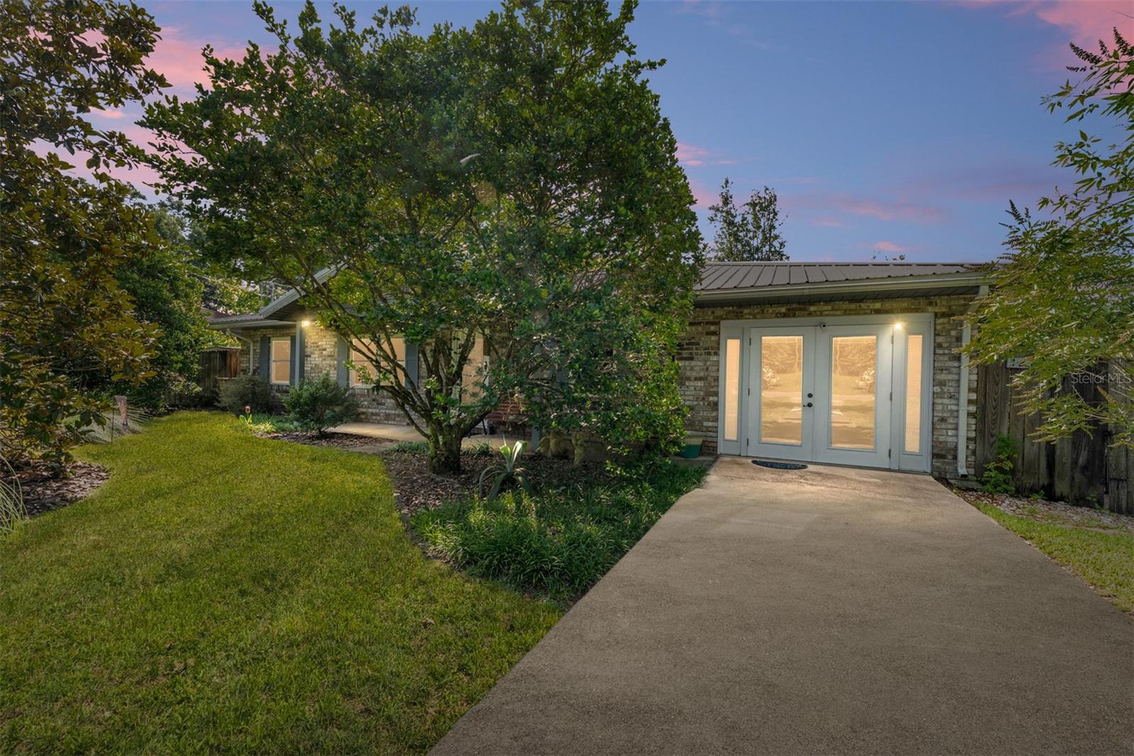 Immaculate charming brick home meticulously cared for and tastefully upgraded throughout. Enjoy the lasting beauty and maintenance free living of this Norwegian brick exterior home with metal roof and all aluminum soffits and facias. Beautiful laminate mahogany flooring throughout living space, engineered wood in bedrooms, tiled baths, quartz counters, stainless appliances, upscale lighting fixtures and ceiling fans, interior wood doors, upgraded insulated glass windows throughout and leaded glass arts and crafts inspired fiberglass insulated exterior doors. Large bonus room study or flex space to utilize as you wish. 1/2 bath large enough to install shower stall if desired. Relax on the covered front porch or spacious rear enclosed custom built screened porch for enjoying the privacy fenced back yard full of flowering schrubs and vines creating an enchanting private oasis. Fiber optic cable just installed in the neighborhood. Great location close to Progress Center, San Felasco Preserve State Park, schools, shopping, I-75 and just a 10 minute commute to Gainesville.