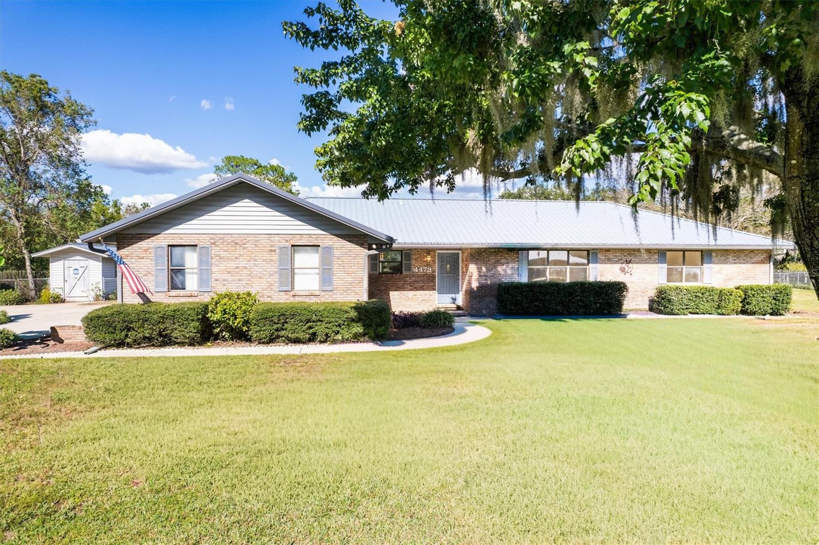 One or more photo(s) has been virtually staged. Welcome to this beautifully maintained 3-bedroom, 2.5-bath brick home situated in the Hidden Hills community in Keystone Heights. This spacious residence offers a thoughtful layout and quality craftsmanship throughout. Step into the welcoming foyer and into the light-filled living room with a cathedral ceiling, perfect for entertaining or relaxing. The open kitchen features a large island, an eat-in dining area, and a great flow for daily living. The primary suite offers a generously sized peaceful retreat, an oversized walk-in closet and a private bathroom complete with a walk-in shower. Guest bedrooms are well-sized and share a full hall bath, which conveniently opens to the large screened back porch. The 12 x 24 tiled and covered porch overlooks a green space, formerly a golf course. A dedicated utility room with a large stainless steel sink and commode can be accessed from the 2-car garage, which also includes a separate golf cart bay. Upgrades and additional features include a 2024 HVAC system, a 2010 metal roof, a detached metal-roofed storage building, security lighting. The home is served by city water and also has well for the irrigation system. The beautifully landscaped yard and peaceful green space backdrop complete the setting. This home combines comfort, functionality, and serene views all ready for you to move in and enjoy. Just minutes from Keystone Heights and Melrose and 24 miles to Gainesville. Buyer to verify all measurements and school zones.