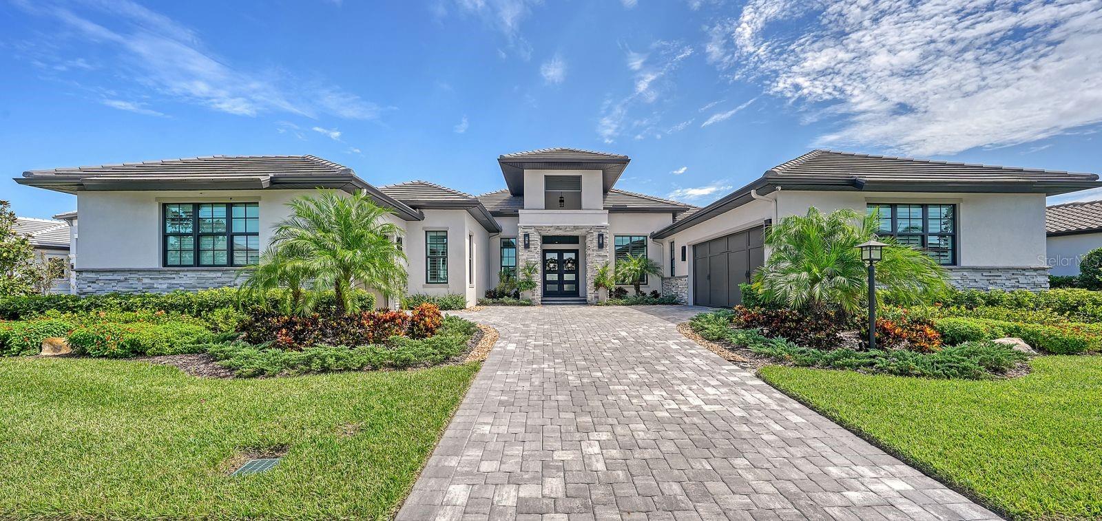 Discover the epitome of luxury living in Waterside's Lakehouse Cove with this meticulously crafted and practically new Arthur Rutenberg Mokara residence boasting impact glass, wood flooring throughout, solid core doors, and exquisite wall and ceiling finishes. The kitchen, with upgraded Omega cabinetry, high-end appliances, hidden pantry, and center island, opens to the spacious great room and dining, leading to a serene lanai with a saltwater pool, spa, and outdoor kitchen set against a tranquil preserve backdrop. This 3,508-square-foot well-designed floor plan includes a spa-inspired primary suite with private work-out room and two dressing rooms, two en suite guest rooms, a versatile bonus room with a custom wet bar, and a sophisticated office with glass corner walls offering a stylish and inviting workspace. Special features include disappearing corner pocketing sliders, built-in gas fire pit outside primary suite, plantation shutters, icynene insulation, sun shelf and waterfall features in pool, epoxy garage flooring, landscape lighting, security, and so much more. As a resident, you'll enjoy access to Waterside's exceptional amenities, including a water taxi service, pickleball courts, resort-style pool, fitness center, playground, and club house. Lakehouse Cove is conveniently located close to the shopping and dining of downtown Sarasota, Waterside Place, Lakewood Main St., and University Town Center. Two major airports, great schools, world-class medical facilities, and famous beaches are all just minutes away. Don't miss the opportunity to make this one-of-a kind property your Florida dream home. Bedroom Closet Type: Walk-in Closet (Primary Bedroom).