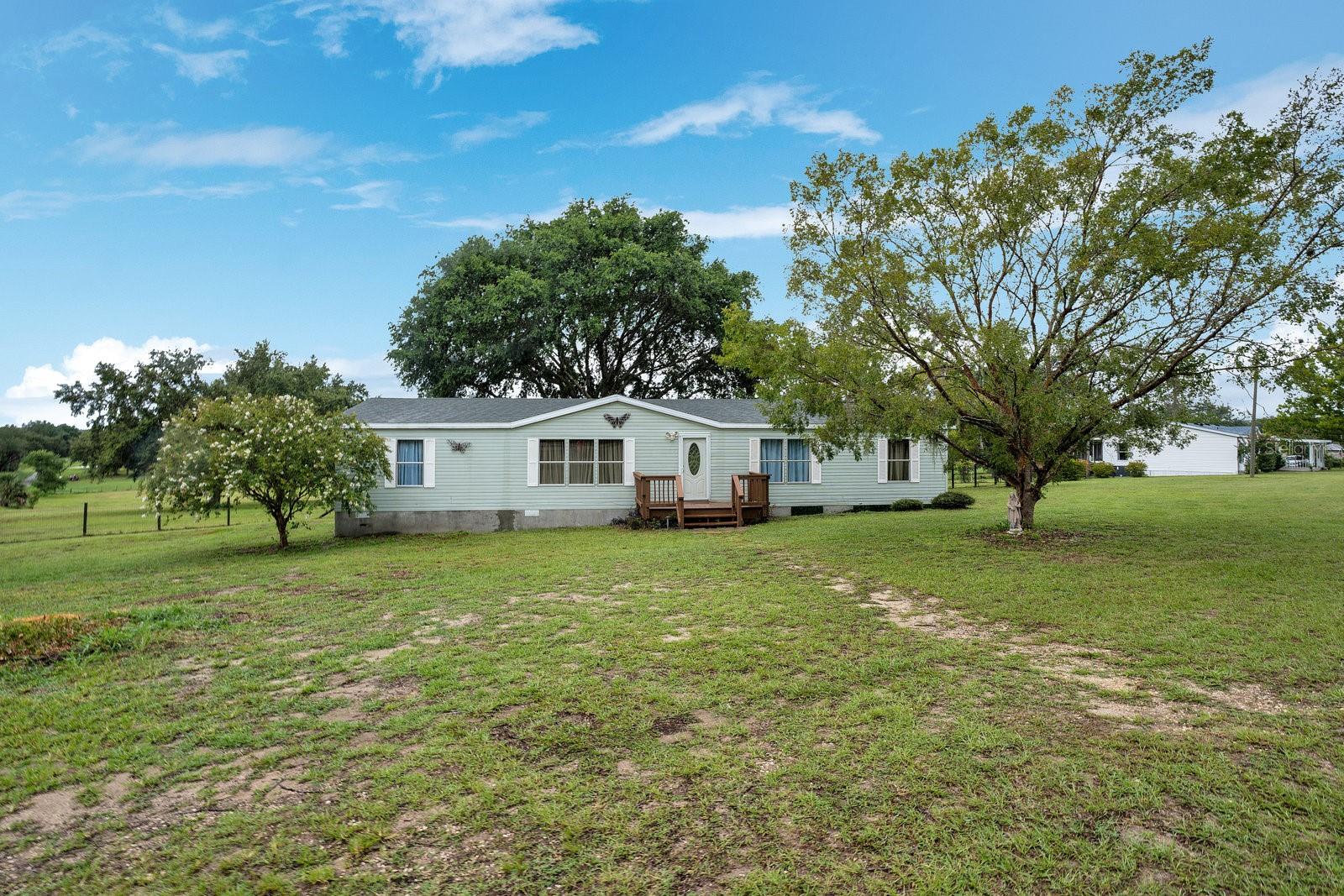 If you’ve been looking for a property with space, privacy, and potential—this is it. Situated on a beautiful 2.5-acre lot, this 4-bedroom, 2-bathroom mobile home is ready for its next chapter. The home features a functional split floor plan with a spacious primary suite, two additional bedrooms, and a comfortable living area filled with natural light. The layout is both practical and flexible, offering a solid foundation that’s ready to live in while you make it your own. Whether you're looking to update a few things over time or live in as-is, the possibilities are endless.
One of the highlights of the home is the screened-in back porch—a perfect spot to sip your morning coffee, watch the sunset, or enjoy the quiet beauty of your surroundings without the bugs. It’s an ideal extension of your living space for relaxing or entertaining outdoors. Outside, the 2.5-acre lot provides plenty of room to spread out and enjoy country living. Bring your animals, your toys, or your dreams of a garden, workshop, or barn—there’s space here for it all. With no HOA, you have the freedom to use the land the way you want. Move in and make it yours—schedule your showing today and come explore the potential this peaceful property has to offer! Located less than one mile from Lake Weir and just minutes from the Villages. **This listing can be purchased individually or as a package with MLS #O6324657, address 14590 SE Sunset Harbour Road**