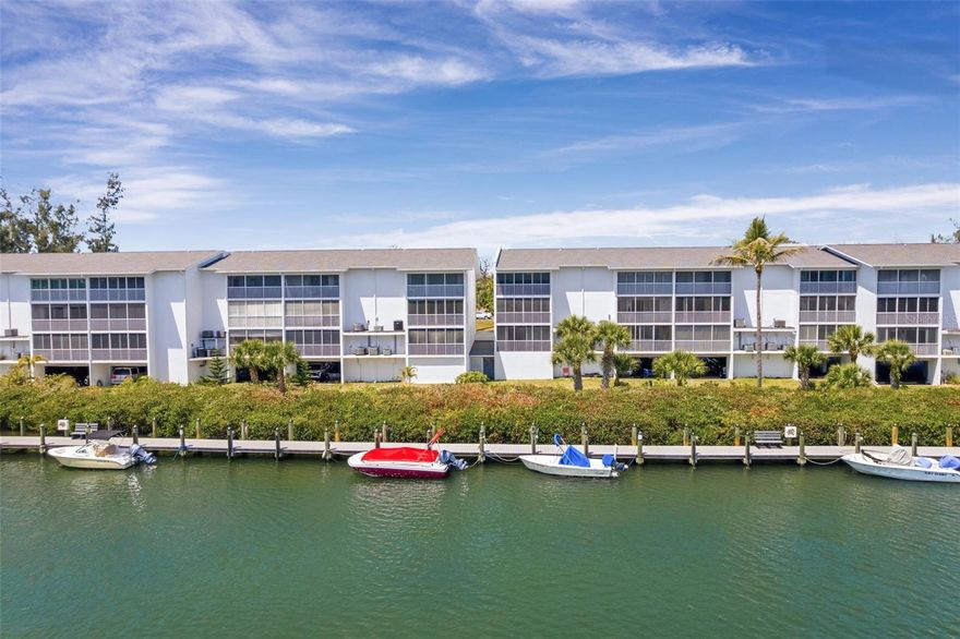 Water views, boats, and breezes—this is the Florida lifestyle you’ve been waiting for. Turnkey furnished with higher-end finishes and furnishings, and perfectly positioned on the water, this beautifully updated 2-bedroom, 2-bath first-floor condo offers 1,087 square feet of relaxed coastal living with serene views of Gottfried Creek. Enjoy direct boating access to Lemon Bay and the Gulf waters with only one fixed bridge, plus community boat slips available for vessels up to 20 feet (waitlist).

Inside, the spacious layout opens into a large living room that flows effortlessly into the kitchen, creating an inviting and airy living space ideal for entertaining or relaxing. Three large sliding glass doors lead to the lanai, filling the home with natural light while showcasing beautiful water views. From the comfort of your living room, enjoy the soothing sounds of nearby water activities and the gentle rustle of palm fronds swaying in the coastal breeze. A built-in curio cabinet with a hidden compartment adds both charm and function to the living space.

The kitchen is thoughtfully designed to impress, featuring granite countertops, rich wood cabinetry with convenient pull-out shelves, a striking glass tile backsplash, and stainless steel appliances including a brand-new refrigerator. Crown molding enhances both the dining area and the tray ceiling in the kitchen, adding an elegant architectural touch. An attached TV/DVD combo is perfectly positioned to be enjoyed from both the kitchen and dining areas, making everyday living and entertaining even more enjoyable.

Step outside to your private screened lanai—the standout feature of this home. With expansive windows, a ceiling fan, and protective screening, this space is ideal for year-round enjoyment, allowing you to relax while taking in tranquil waterfront views and refreshing coastal breezes.

The primary suite is generously sized and beautifully furnished, offering direct access to the lanai, a large walk-in closet, and an en-suite bath featuring quartz countertops and a beautifully tiled shower with stone pebble flooring for a spa-like feel.

The guest bedroom and bathroom are equally impressive, showcasing beautiful wainscoting and chair rail detailing that elevate the space. The guest shower features an attractive large tile surround with decorative blue tile accents, unique stone flooring, and a rain showerhead—creating a stylish and relaxing retreat for visitors.

Boating enthusiasts will appreciate the community boat slips (up to 20 feet, waitlist) with access via Gottfried Creek, offering one fixed bridge en route to Lemon Bay and the Gulf. As an added bonus, two kayaks convey with the sale, so you can begin exploring right away from the on-site launch.

Additional conveniences include a covered parking space to keep your vehicle cool, along with a private, locked storage cage in the same area—perfect for storing beach gear and water toys.

The community enhances your lifestyle with a heated pool, tennis courts, and a vibrant social calendar, creating a welcoming and active environment for residents.

Whether you're seeking a full-time residence, seasonal retreat, or investment opportunity, this waterfront gem delivers the perfect blend of comfort, convenience, and elevated coastal charm.