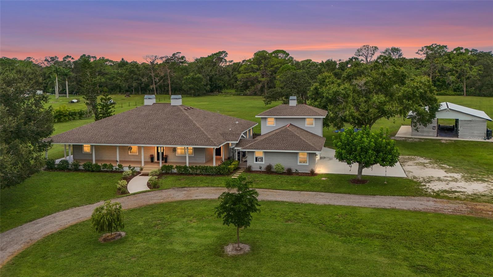 Sprawling 5+ acre estate effortlessly blends elegance with country charm. This property is an absolute MUST SEE! The home was nearly fully updated in 2021, with the exception of the primary bath and secondary bath, blending modern enhancements with classic charm. Zoned for horses and farm animals, this exceptional retreat invites your boat, RV, and gardening dreams, creating the perfect backdrop to embrace country living and adventure all while being minutes away from town. As you arrive, you will be welcomed by a picturesque wraparound porch that leads to a West-facing lanai, offering breathtaking sunset views. Step inside to discover a spacious and modern interior featuring three well-appointed bedrooms plus a flex room which can be used as a guest bedroom, media room, office, or den. At the heart of the home, you'll find the elevated kitchen featuring beautiful dolomite countertops with soft gray veining that flows across the luminous white surfaces. These elegant countertops pair perfectly with the new cabinetry, sleek appliances, and modern finishes—creating a space that's ideal for both casual living and entertaining. Updates to the home and property include: Newer Roof (2017), LVP flooring throughout (2021), Entire interior repainted (2022), Kitchen remodel (2022), New AC (2022), 66 yards of Concrete added to property which includes driveway entrance apron, 3 car garage extension, barn/workshop (2023), New Challenger Well and Water softening system throughout entire home (2024), All Exterior trim and porch repainted (2025). Six horse-stall barn was converted into a workshop/hobby shop in 2023 providing an oversized workshop space where you can park extra cars, small boats, trailers, 4 wheelers, & lawn equipment. The three car garage has an unfinished upstairs apartment space. 20 minutes from Historic downtown Sarasota, and less than 10 minutes to I-75, UTC, shopping and dining. This move in ready retreat is a rare opportunity to enjoy the very best of country living, with city convenience.