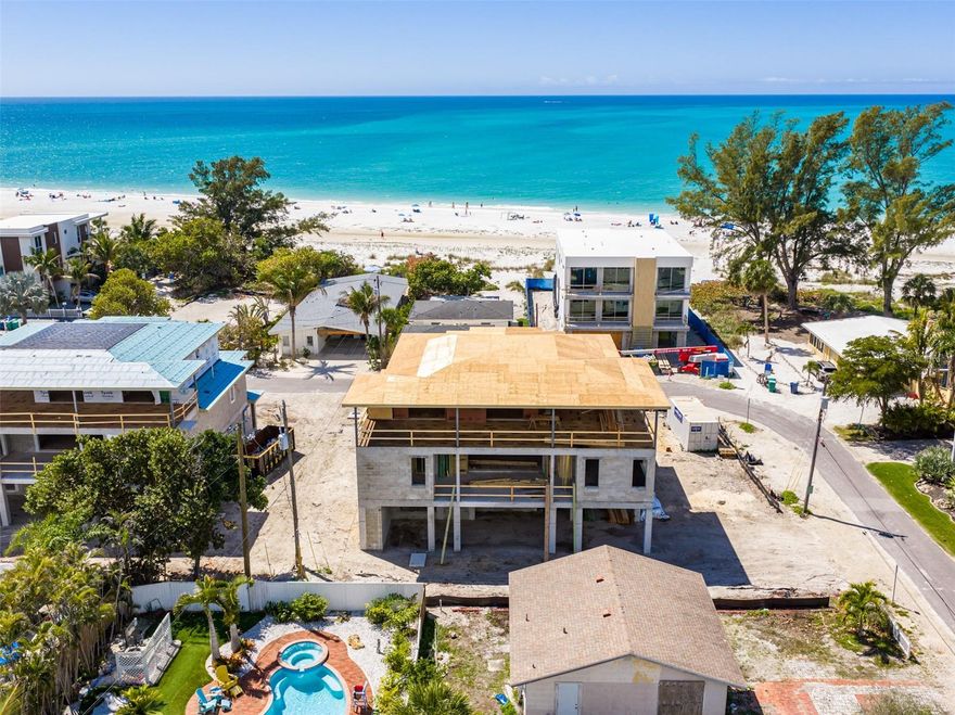 Under Construction. Blending modern coastal construction with Old Florida charm, 107 Tuna Street offers a level of design, scale, and positioning that is seldom found on Anna Maria. Just 50 feet from sugar-white sand and set on an oversized corner lot along the coveted North End, this residence enjoys a peaceful setting away from the activity of the public beaches, offering a more private, “locals’ luxury” experience just steps from the Gulf’s iconic turquoise waters. The residence’s Key West–inspired architecture sets the tone with deep balconies, porch brackets, generous openings, and a layout that favors natural light and easy indoor-outdoor living. Built with full concrete block construction and engineered to 2026 Florida hurricane standards, the residence offers exceptional durability and peace of mind inherent to premier coastal living. Upper floors are thoughtfully oriented to catch optimal light and frame coastal views, so the home feels bright and connected to its setting throughout the day, even before you step onto the balconies to watch sunsets that stop everything. Inside, vaulted and cathedral ceilings create volume throughout the open-concept living spaces. The main-level primary suite offers both convenience and privacy, complemented by accessible design features including wider doorways, a full bath, and thoughtful flow for long-term livability. A three-stop elevator connects all levels with ease. The kitchen, with its custom wood cabinetry, is designed as both a showpiece and a workspace, anchored by a full Thermador appliance suite, including a 7-burner range, integrated refrigeration, and dishwasher. Adjacent living and dining areas extend effortlessly outdoors, where 3,000+ square feet of covered and open-air living space transforms the home into a true coastal retreat. Here, the outdoor environment is an extension of your everyday living space. A fully integrated alfresco kitchen anchors the space, complemented by three distinct dining areas designed for everything from casual mornings to large-scale entertaining. The expansive 48’ x 25’ free-form pool and spa create a resort-style centerpiece, surrounded by three lounging areas near a private volleyball court. Positioned just a 120-second stroll from one of Anna Maria Island’s most serene stretches of powdery white sand, the home offers immediate access to the Gulf without sacrificing privacy. Just moments from the charm of Pine Avenue with boutique shopping, cafés, and local favorites like Dips and The Donut Experiment, plus local or even waterfront dining at the Sandbar, The Porch, and The Waterfront, all just blocks away, making everyday living feel like a vacation. With projected strong rental income potential, a six-car garage, and a delivery timeline of Summer 2026, 107 Tuna Street represents a compelling opportunity to secure a newly built, design-forward residence in one of Anna Maria Island’s most desirable and tightly held enclaves. Nearby marinas, boating access, and waterfront parks enhance the island lifestyle, while the cultural amenities of downtown Sarasota, St. Armands Circle, and Longboat Key are all within easy reach. SRQ International Airport is approximately 40 minutes away, offering convenient access. This is a setting that balances seclusion and accessibility, where everyday feels like a vacation, and everything you need is effortlessly within reach.