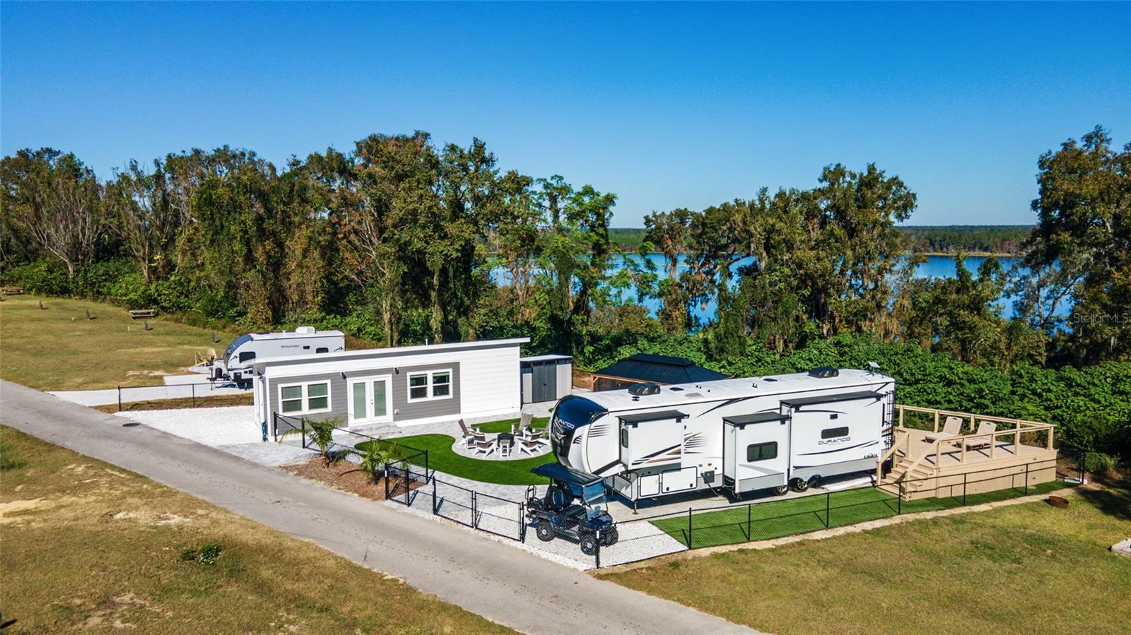 Amazing property in Oklawaha Overlook Condo with the best views in the neighborhood overlooking Lake Ocklawaha! NEW 2023 CONDO AND TWO deeded lots ~ including screened gazebo with TV, pavers, artificial turf, shed, and fire pit area. The lots are fenced with 2 gates. Beautiful 2023 condo has OPEN FLOOR PLAN with LVP throughout ~ 1 bedroom, 1 bathroom, including laundry washer/dryer. 2023 KZ Durango Gold 5th wheel plus office or mid-bunk options is available separately for $115k (on 12x40 concrete pad) and has a custom deck made of red cypress hardwood, Generac gas generator, Starlink internet modem/antenna, and 7 year transferrable full on-site maintenance contract. This property is a great family retreat ~ multi family ~ investment property for AirBnB/Vrbo. Amenities for all ages include a pool, clubhouse, dog park, beach area, playground, corn hole, volleyball, ATV riding trails, nature trails to lake and outlook, and much more. Close to downtown Fort McCoy with grocery store, doctor's office, pharmacy, hardware, gas station, pizza delivery and 30 miles to Ocala's conveniences. For the outdoor enthusiast, lakes, springs, and Ocala National Forest are close by for you to enjoy fishing, hunting, hiking, boating/canoeing/kayaking, and ATV trails! HOA includes electric, water, sewer, trash, and amenities. See attachments for more info. Lot 350 is for sale for $105k and is being rented for $1,000/month through the park. The 2022 20' Forest River Wolf Pup is for sale for $25k.