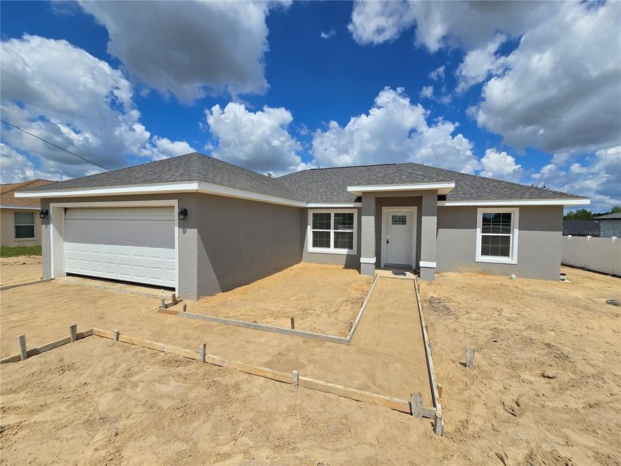 Come see this wonderfully styled, 3 bedroom, 2 bath, 2 car garage on a .24 AC LOT in the very popular Silver Springs Shores area. This home features a split plan, high ceilings & QUARTZ STONE counters in the KITCHEN, BATHROOMS & WINDOW LEDGES! When you step in side, you will notice the open design with tall ceilings and a split floor plan. The primary bedroom features an oversized closet & en suite bathroom with A FULLY TILED, EZ ENTRY SHOWER & linen closet. The kitchen, has whisper quiet drawers & UPGRADED cabinets with stylish knobs. Gorgeous sink with a beautiful open view. DELUXE SMART APPLIANCE PACKAGE INCLUDES Stainless steel Fridge, Dishwasher, Stove & Microwave comes with the home. A beautifully patterned Quartz counter island comes with room for chairs. Nearby, you have access to the laundry room & garage via a handy pocket door. Across the house, the secondary rooms share the bathroom and will have good space for a full size bedroom set, office, or a game room. The choices are endless! Ample closet space has been supplied as well for all of their storage needs. The .24 acre lot gives you plenty of room for all of your toys! NOT IN AN HOA so you are free to build a fence, add a pool, do what you want, how you want! On a well and septic system so NO UTILITY BILLS is also a great plus! If you install back up power in preparation for any possible outage, you will still have use of water and sewer as long as you have electric! Close enough to give you access to Belleview, Summerfield, The Villages, The Interstate and beyond. Less than 12 min to Wal-Mart, Publix, Aldi & Save a Lot, The post office, 3 auto parts stores & car washes as well as many food & medical offices nearby for ease. A short drive in either direction will lead to Ocala's downtown square or to our famous Lake Weir, where you can boat, kayak, jet ski, or enjoy a meal on the lake over looking the sunset. USDA, First Time Homebuyer & Veteran friendly! Almost completed, you can be in QUICKLY!