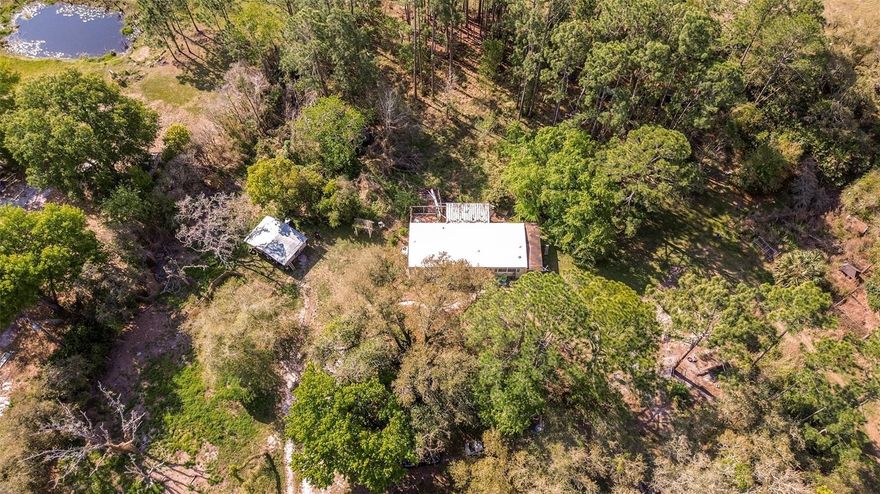 Looking for acreage, privacy, and a property you can make your own? This 4.8-acre property in Lake County has a lot of potential for the right buyer willing to put in some work.

The land is fully fenced and gated with a private entrance and U-shaped driveway. It backs up to pasture land and is surrounded by pine trees, giving it a quiet country feel. There is an older pole barn toward the back of the property, along with a storage shed, chicken coop, dog pen, and RV setup capability already in place.

The mobile home on site offers 3 bedrooms, 2 bathrooms, wood flooring throughout, a new AC unit, a screened back porch, and side porch. The home does need updating and repairs, and the land has not been maintained over the last year, but for someone looking for a fixer upper, investment opportunity, or a place to live while building a future home, there is a lot to work with here. The outside patio was damaged during the last hurricane, although the screened porch is still intact.

Located in Lake County with low yearly taxes, this property offers a country setting while still being within reach of DeLand, Eustis, and Mount Dora.