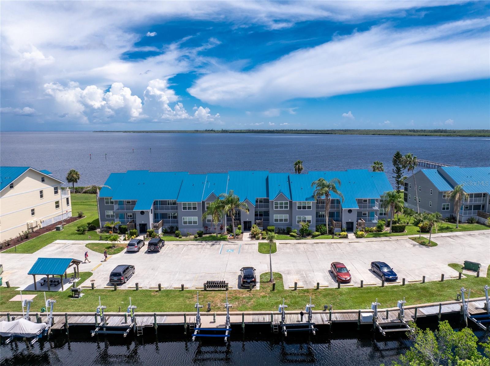 Tropical Waterfront Retreat offered Furnished & Turnkey. Escape to your own waterfront sanctuary, just bring your boat and your toothbrush, it’s the ultimate Florida getaway! This beautifully renovated one-bedroom, one-bath condo blends tasteful tropical charm with modern conveniences. Step inside to discover a light, open interior adorned with coastal paint hues, barn-style doors with frosted glass inserts, and modern LED lighting throughout. The living room invites you to relax with light wood and mirror accent walls, a big-screen TV, ceiling fan, and easy access to the lanai that’s just feet from the water. The updated vinyl flooring and stylish roll-down blinds complement the space beautifully. The fully renovated kitchen features sleek gray wood cabinetry, quartz countertops, attractive tile backsplash, and a GE stainless steel appliance package. Additional storage under the breakfast bar, designer touches with jellyfish pendant lighting, make it both functional and beautiful. The spacious primary bedroom offers a king-size bed, walk-in closet, and direct access to the tastefully updated bathroom featuring a barn-door-style glass shower, modern vanity, bidet commode, and updated lighting. Convenience is key with a GE washer-dryer combo tucked away in the utility closet along with a 2021 A/C and water heater. Step onto the covered lanai with its automatic privacy sunshade and soak in breathtaking views of Charlotte Harbor and the Myakka River. Whether you’re sipping morning coffee or winding down after a day on the water, the scenery is unmatched. This gated community offers resort-style amenities, including a massive harbor-front pool, fitness center, tennis and pickleball courts, grilling stations, community room with library and billiards, and a first-come, first-served boat dock with relaxing seating areas. Beyond your doorstep, enjoy world-renowned top-rated beaches, convenient shopping along SR-776 and Murdock Circle, and the excitement of Tampa Bay Rays spring training nearby. For anglers, Charlotte Harbor and Boca Grande Pass provide world-class fishing for redfish, snook, and tarpon. With impact-resistant windows, metal roof, vinyl siding, and fully furnished turnkey convenience—just bring your toothbrush—this condo is perfect for full-time living, a vacation home, or an investment property. Discover the perfect blend of tropical relaxation and waterfront lifestyle—your harbor retreat awaits!