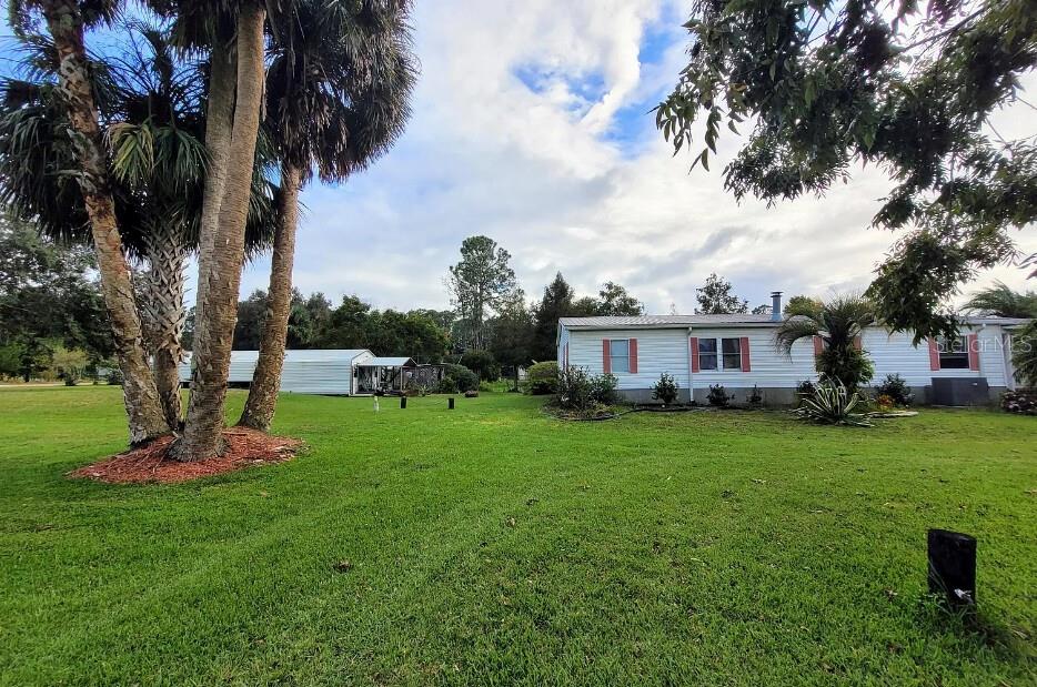 Stop Looking! This Is The Place for You! Nestled just blocks from the beautiful St. John's River, on the border of Georgetown, this charming 3-bed, 2-bath home is located on a 1-acre corner lot with serene views of a small scenic lake. The country setting offers tranquility and natural beauty, making it the perfect escape. As you step through the hearty wooden door with an amazing porthole window, you'll be greeted by the warmth of the Cypress wood room. A nautical-inspired mural adds character, surrounded by tinted windows, a corner fireplace, and glass French doors that open to the back deck—ideal for relaxing or entertaining. Open living room features a wood-burning fireplace, a breakfast bar in the kitchen, and a walk-in pantry. The split bedroom layout provides privacy, with a master bedroom featuring an ensuite bath. The large back porch has been updated with a new screened-in area for added comfort. Pictures truly don't do this property justice! The detached workshop offers additional covered parking, large enough for your boat, and comes with electricity. Recent upgrades: a newer stove, fridge, washer, dryer, & new water system. The yard is beautifully landscaped with a variety of fruit trees, palm trees, and lush greenery. Additionally, the .43-acre adjacent lot is available for sale, perfect for expanding or enjoying even more space. The dock is in need of repair, and access to it is restricted. DO NOT WALK ON THE DOCK