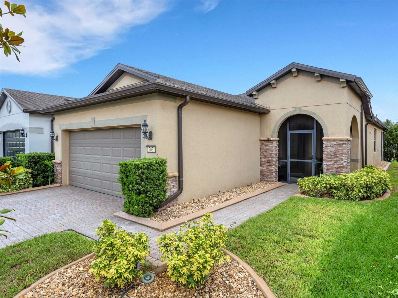 This cozy Steel Creek model located in the beautiful and desirable Del Webb Orlando 55+ community has 2 BR and 2 baths. Before entering the home notice the concrete curbing around the entire house that has been installed for ease of landscape maintenance. Stone facade, garage door keypad, the beautiful 8' leaded glass front door and rear security lights are upgrades that were installed when the home was built. The front entryway has been screened and provides a restful area to enjoy passing the time. Once inside the foyer, you can appreciate the open floorplan. Nestled in the front section of the room is a kitchen nook, which could also be used as a small office or sitting area. The solid wood cabinets are complete with granite countertops and are complimented by the stainless steel appliances, including a NATURAL GAS range. A large island provides space for that quick breakfast or for serving space for a larger meal. The great room and dining area are located off the kitchen near the back. Outside, through the triple sliding glass door is a peaceful screened lanai, complimented with a paver patio, that offers a place for morning coffee or simply relaxing. The owner’s suite is located in the rear of the home and features an on-suite with large walk-in closet, granite countertops, a linen closet and a large shower. The second bedroom and bath are located near the front of the home boasting privacy for guests. The second bathroom has been upgraded to a walk-in shower. When the power goes out, the 22K GENERAC GENERATOR kicks on and keeps the household running! The $277 monthly Del Webb HOA fee includes yard maintenance and exclusive access to resident-owned 30,000+ SF Montecito clubhouse and amenities. $425 semi-annual HOA fee provides 24x7 staffed security gate and master association-owned private road maintenance. Adjacent to recently renovated 18-hole White Heron Golf Club. DEL WEBB ORLANDO is a 55+ community with a tavern, indoor walking track, indoor and outdoor pools and spas and fitness center. Outdoor activities include tennis, bocce, basketball and pickleball. Miles of biking and walking trails within Ridgewood Lakes gated community. Located conveniently to shopping at Posner Park (4 miles), Disney World, Universal Studios, Orlando & Central FL entertainment nearby. Easy access to I-4, medical facilities, airports & Sunrail Station. Advent Health hospital is 3 miles away.