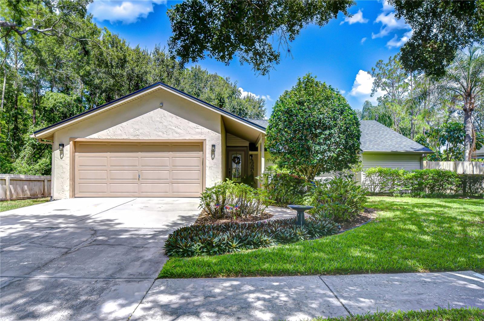 Fall in love with this peaceful retreat in a sought-after location! This spacious, impeccably maintained 3-bedroom, 2-bathroom home offers over 1,800 square feet of comfortable living space, nestled on a tranquil lot with lush, mature landscaping and a fully fenced yard. A long, covered entry porch leads into an airy open foyer, setting the tone for the warm and welcoming atmosphere that flows throughout the home. The semi-open layout combines a charming family room with soaring sloped ceiling, a spacious eat-in kitchen, and a large formal living and dining space. The beautiful kitchen is a true centerpiece, with a generous dinette area, dual oven range, ample cabinet and granite counter space, closet pantry, and its best feature -- full-size sliding pass-through windows to the patio bar counter, perfect for effortless entertaining. Adding daily convenience, the laundry room, with extra pantry and utility storage, is hidden by a pocket door off the kitchen and provides exterior access to the backyard. The inviting family room is sure to become a favorite gathering spot, with a cozy wood-burning fireplace and mantle flanked by ceiling height built-in shelving, and light-color laminate floors that continue into all bedrooms. French sliding glass doors lead out to an expansive covered, screened patio with beautiful ceramic tile floors, dual ceiling fans, and a wrapped bar-height granite counter that flows to the kitchen -- you will love this space for entertaining, al fresco dining, or simply lounging and unwinding from the hustle and bustle. The manicured and fully fenced backyard is a haven for quiet mornings, pets, or play -- it features an extended pavered walkway, storage shed, and plenty of room for a future pool. Inside, the spacious combination living and dining area, adorned with crown molding, is uniquely configured and offers plenty of design versatility. The comfortably sized primary bedroom also features crown molding and provides an unassuming glass slider for private access to the patio. The en-suite primary bathroom boasts a beautiful granite-topped vanity, skylight, jetted tub, and walk-in closet with a storage system. The serene guest bathroom was recently remodeled and features a skylight for extra natural light. Both secondary bedrooms are spacious, and the common hallway provides additional full-size built-in closets for ample extra storage. Additional features include: NEW ROOF in 2022; new water softener with 10-year warranty; new water heater; attached two-car garage with workshop area, shelving, and hanging racks; pull-down ladder to access an abundance of attic storage; generous insulation for energy savings; irrigation system, and so much more. Not only will you love this house, but there’s so much to love about its location – nearby access to the expressway and a quick and convenient drive to a plethora of everyday conveniences, as well as a variety of restaurants and shopping options in Carrollwood, Citrus Park, and Northdale. Country Place is a family friendly community with a low annual HOA fee offering parks, playgrounds, basketball courts, and ample sidewalks for walking or biking.