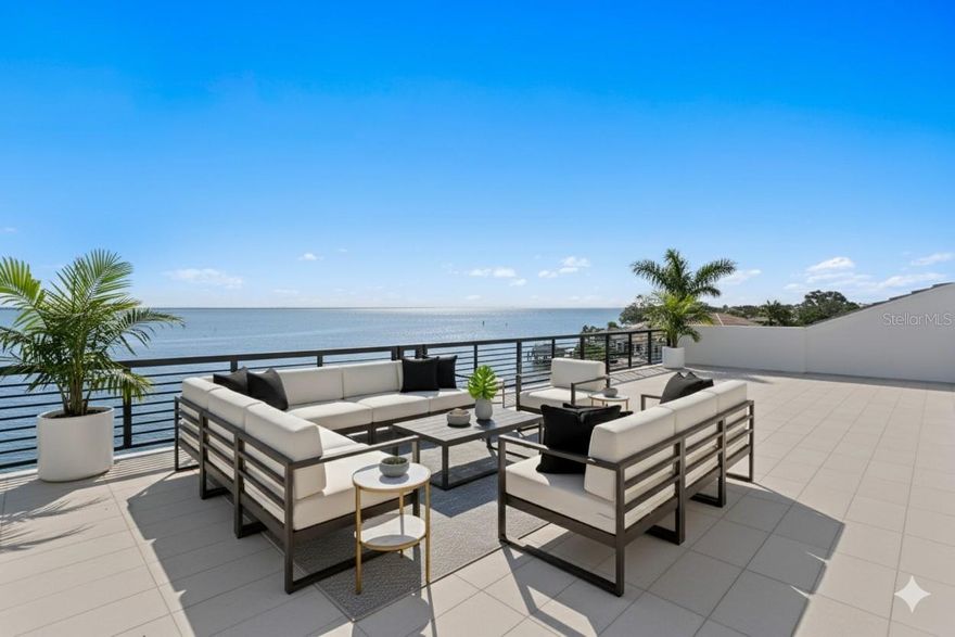 Recently completed to the highest standards, this stunning new construction Venetian Isles waterfront residence blends refined luxury with cutting-edge engineering. Built on pilings and reinforced with rebar/concrete, this elevated home offers unmatched strength, stability, and peace of mind. Poised gracefully at the edge of Tampa Bay, enjoy sweeping, uninterrupted views that extend across the glistening water to the skyline of St. Petersburg. Built by Tide Homes, a professionally designed interior provides a sophisticated aesthetic and curated elegance. From the moment you step inside, you’re welcomed by warm Chesapeake hardwood floors and a serene palette of premium finishes. The expansive main living area delivers sweeping floor-to-ceiling water views and a dramatic gas fireplace and feature wall which integrates a glass-enclosed wine cellar that anchors the formal dining area. A sleek chef’s kitchen is crafted with carbon-neutral Dekton countertops and backsplash, Thermador and Bosch appliances, a butler’s pantry/full prep kitchen with additional dishwasher and refrigerator, along with an expansive waterfall island and access to the gracious main terrace with outdoor kitchen. The main living level also features 3 ensuite guest bedrooms and one of 2 laundry rooms with LG appliances. Upstairs, a versatile bonus room provides the perfect location to relax, indulge in a competitive game night, or entertain with ease. A custom entertaining wet bar and media wall set the tone, while expansive glass doors flow to the waterfront terrace, along with spiral stairway access to the rooftop terrace and unmatched panoramic views. Through the double doors, a private primary suite greets you with spectacular views, an impressive custom his and her closet/dressing room, along with a spa-inspired bath offering backlit mirrors, expanded glass shower and deep soaking tub. This private level also features a powder bath and laundry room, along with an additional ensuite guest bedroom and walk-in closet. Experience exceptional Florida living outdoors, with over 750 feet of covered lanai space, saltwater heated pool and spa that overlook the glistening bay, along with a private dock for endless water recreation. From the fortified piling construction and 3-stop commercial-grade glass elevator—to marine-grade outdoor cabinetry, dual laundry rooms, and a 3-car garage, this modern waterfront escape delivers uncompromising strength with premium building compliance, PGT impact-rated windows and sliders, and impact garage doors. Located in one of St. Petersburg’s finest neighborhoods, enjoy convenient access to parks, recreation and award-winning beaches, while only minutes to downtown St. Petersburg’s vibrant arts and culinary destinations.