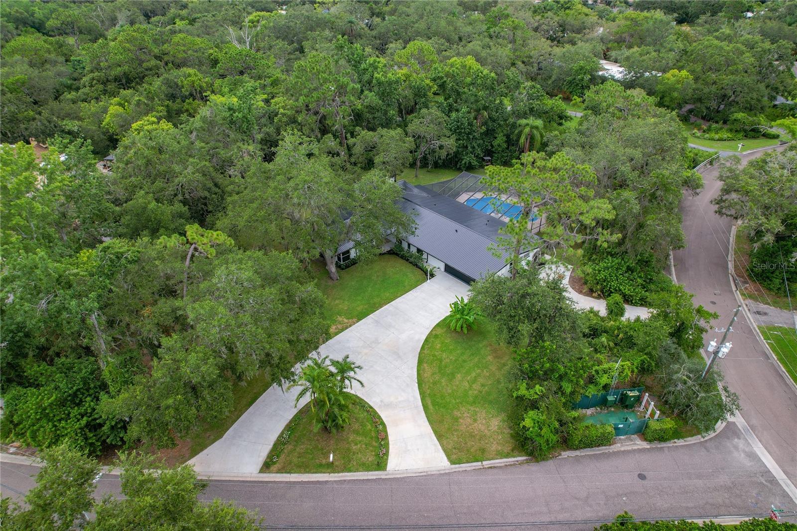 Tucked away in the coveted Spanish Trails community of Dunedin, this Mid-Century Modern Glam Estate is the perfect blend of style, privacy and convenience. Set on a lush and serene 1.04-acre conservation lot, this 4-bedroom, 4-bathroom home spans 2,536 square feet and welcomes you with an impressive circular driveway and stunning curb appeal. Step inside and discover an architectural gem where luxury meets modern living. Every inch of this home has been thoughtfully updated in 2024 ~ including a sleek 24-gauge metal roof, new AC, fresh interior and exterior paint, brand-new flooring throughout, fully remodeled bathrooms, a show-stopping kitchen, new hardware and fixtures, updated windows and doors and an epoxy-coated pool finish. It’s like stepping into new construction with all the character of a timeless design.
The gourmet kitchen is a true centerpiece, featuring gleaming Calacatta quartz countertops, gold accents, stainless steel range hood, push-to-open pantry storage and a waterfall island perfect for entertaining. Vaulted ceilings with exposed wood beams and a dramatic stone fireplace wall add warmth and charm to the spacious living room. Floor-to-ceiling windows offer a front-row view of the lush backyard and fill the space with natural light. With a split-bedroom layout and custom built-in closet shelving in every room, this home provides both privacy and practicality.
Step outside to your private oasis ~ a screened-in patio with a deep sparkling pool, surrounded by travertine decking and mature tropical landscaping. Whether you're soaking in the sunshine or relaxing under cover, this outdoor space is designed for year-round enjoyment. And for the hobbyist or adventurer, the oversized 4-car tandem garage plus ample outdoor parking provides plenty of room for trucks, RVs, boats and more.
This home sits high and dry ~ just blocks from the water but safely out of the flood zone. The location is unbeatable, just a few minutes from Downtown Dunedin, the Dunedin Causeway and Honeymoon Island. Golf lovers will appreciate proximity to Dunedin Golf Club, Chi Chi Rodriguez Golf Club and Innisbrook Golf Resort. Enjoy a vibrant local lifestyle with nearby parks, art centers, shopping, dining, breweries and the scenic 47-mile Pinellas Trail. With no HOA or deed restrictions, this is true Florida living ~ elevated. Welcome to a one-of-a-kind estate where style, comfort and location come together beautifully.