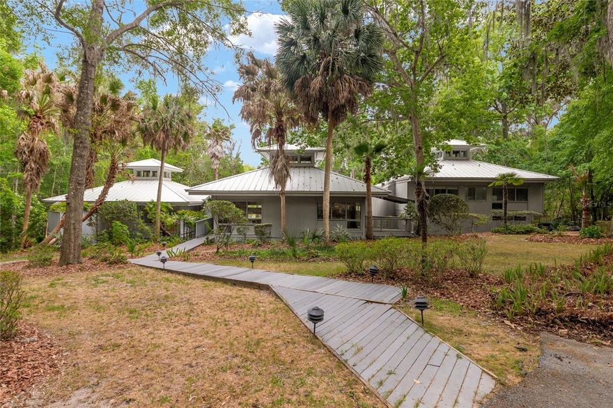 Experience refined, contemporary living in this extraordinary 5-bedroom, 5.5-bath estate, originally featured in Southern Living and designed by acclaimed architect Robert Taylor. Thoughtfully crafted with a unique multi-wing layout, this residence offers both privacy and seamless spaces for gathering.

Set on an expansive 2.39-acre lakefront lot, the property is a true sanctuary, home to a diverse array of birds and native wildlife, creating a peaceful, nature-rich environment that enhances everyday living.

Inside, the home is defined by dramatic architectural elements, including soaring ceilings with exposed beams and an abundance of natural light streaming through expansive rear-facing windows. These striking design features frame tranquil lake views and overlook a distinctive, Florida-shaped pool with relaxing waterfalls backdrop, creating a seamless connection between indoor and outdoor living.

Recent improvements provide both style and peace of mind, including a newly installed metal roof, an updated HVAC system, a new pool heater, a new water heater, and two beautifully renovated bathrooms featuring modern finishes.

The heart of the home is a fully reimagined kitchen, designed for both everyday living and entertaining. It showcases premium finishes, quartz countertops, custom cabinetry, a built-in dining nook, and high-performance appliances, including a 48-inch BlueStar gas range. This space flows effortlessly into multiple living and dining areas, along with a welcoming family room complete with a fireplace.

The primary suite is privately situated in its own wing, offering a quiet retreat with direct access to a screened outdoor deck that includes a hot tub and sauna—ideal for relaxation at any time of day. Additional bedrooms are positioned in a separate wing with their own shared lounge area, providing comfort and flexibility for guests or extended living arrangements.

Outdoors, the property is surrounded by lush, mature landscaping that enhances the sense of privacy and creates a serene, resort-like setting. Whether enjoying peaceful lakefront views, observing local wildlife, or entertaining poolside, this home offers a rare blend of architectural distinction, natural beauty, and modern comfort.

Ideally located just minutes from town, this exceptional property offers the perfect balance of convenience and seclusion. Enjoy quick access to nearby parks, scenic walking and nature trails, and some of Gainesville’s most treasured natural attractions, including Devil’s Millhopper Geological State Park and San Felasco Hammock Preserve State Park. Tucked away in a peaceful, private setting yet close to shopping, dining, and everyday amenities, this home delivers a truly unique lifestyle surrounded by nature.