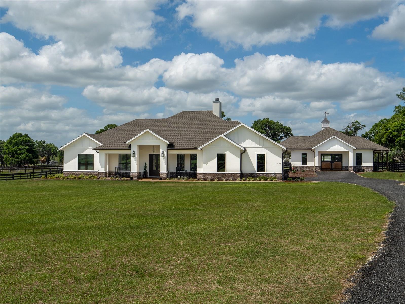 Located just 20 minutes from the World Equestrian Center, this 9.90-acre farm is set within the gated equestrian community of Bellemont Farms. Designed with attention to both form and function, the property is fully fenced and thoughtfully laid out for equestrian living. The well-equipped 4-stall center-aisle barn features custom European stall fronts with Dutch doors, stall mattresses, and spacious overhangs outside each stall. Additional barn features include a temperature-controlled tack room, feed room, bathroom/laundry area, and a separate storage room. A whole-house fan installed in the cupola, equipped with a timer, provides added ventilation. The wash rack is outfitted with hot and cold water and heaters for added convenience. For additional practicality, the barn includes an RV hookup, and a covered walkway connects the barn to the main residence, offering sheltered access regardless of the weather. Four manicured paddocks provide generous space for turnout, and residents enjoy direct access to the community bridle path for riding within the subdivision. The 3-bedroom, 3-bathroom home showcases attention to detail throughout, featuring an open-concept design with engineered hardwood and porcelain tile flooring. High ceilings further enhance the sense of space, with 10-foot ceilings throughout and 11-foot ceilings in the family room and master bedroom. The chef’s kitchen boasts custom cabinetry with quartz countertops, a farmhouse sink, a Viking professional series gas range, Bosch appliances, a large walk-in pantry, and a spacious kitchen island that is topped with hickory wood and equipped with a sink for preparing meals for guests or entertaining. The master bathroom offers a spa-like retreat, complete with a standing air jet tub, a large walk-in shower, and dual designer vanities. The rear patio includes stub-outs ready for an outdoor kitchen sink and gas cooking, offering the opportunity to create a customized outdoor entertaining space. Completing the property is a 3-car garage with an electric vehicle charging station and a generator that powers both the home and barn, all set in a peaceful, upscale equestrian setting.
