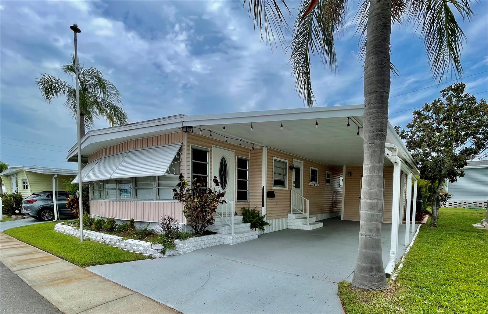 Beautiful double wide with 2 bedrooms, 2 bathrooms and a Florida room with central AC. This home comes with very updated furniture (mostly mid-century decor), outside patio furniture is nice as well (currently stored in the Florida room). Home has been mostly updated, very light, bright and stylish. The front Florida room right now has extra furniture in it, but half of it goes on the patio out back. Roof-over is approx 15-18 years old. Must see this home.
Sunset Palms is in close proximity to the beaches, airports, I – 275, churches, restaurants, all kinds of shopping, etc.… This park is 1 of Pinellas County‘s best kept secret in my opinion, very inexpensive living at ONLY $183.05 per month which includes all the amenities one could want; WATER, SEWER, and TRASH, owned clubhouse, escrows are fully funded, beautiful heated pool and spa, fitness center, library, shuffleboard, billiard table, and a small lake at the back of the park, laundry room, and your very own private entrance to the super Walmart… on foot, bicycle or golf cart… Etc., etc.