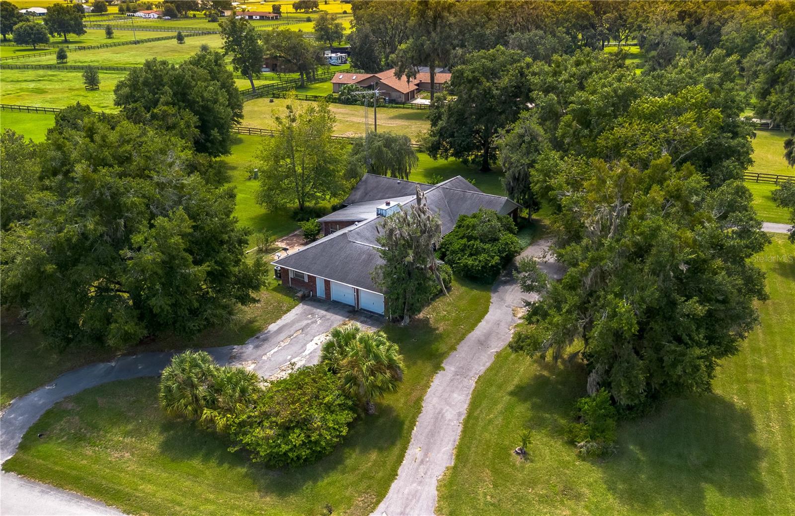 Set on a spacious corner lot in the quiet Hickory Meadows neighborhood, this solid brick home is a great opportunity for those looking to renovate and make it their own. Whether you’re an investor seeking your next project or a homeowner eager to create a custom space, this property offers the size, layout, and location that make it well worth the effort. Nestled on 1.63 acres and gently shaded by mature trees, the home features 4-bedrooms, 2-full baths, 1-half bath with over 3,000 square feet of living space. Much of the carpet and wallpaper has already been removed, leaving a blank canvas ready for transformation. Inside, a spacious living room showcases wooden cathedral ceilings and a brick fireplace that gives the room a warm, inviting feel. The kitchen is nicely designed and features generous counter space, lots of storage with wooden cabinetry, a center island with a flat cooktop and matching range hood, wood-paneled fridge, and an adjacent breakfast nook and formal dining area. The indoor laundry room is an added functional space with a utility sink and extra storage. The primary suite is a nice retreat with plenty of potential with wood-beamed ceilings, dual walk-in closets, and a private en-suite bath. Just off the living room is a large Florida room with a built-in wet bar, which provides easy access to the backyard and is an ideal space for future entertaining. An oversized side-entry garage and circular driveway offer plenty of parking and convenience. With solid construction, a flexible layout, and a great location, this home is ready for someone with vision to bring it to the next level. Enjoy the peaceful setting with the added benefit of being close to both Ocala and Gainesville, offering a perfect balance of privacy and accessibility!