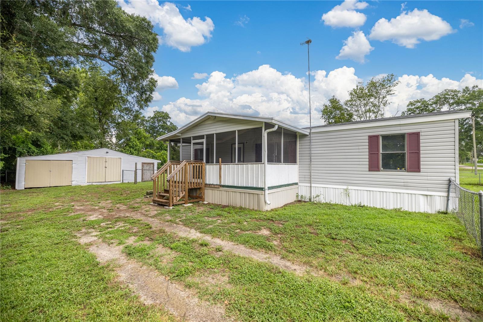 3 bedroom 2 bath Doublewide, New roof 2025, A/C 2023. Some interior updates done and some to go ( flooring and trim work ) Home has a Screened front porch and covered back porch. Split floor plan, walk in closet, inside laundry area. A Chain link fenced Backyard for the pooch to roam. Multiple uses for the 20 x 31 Utility building where the center section has two rooms with electrical. The two sides of the building are perfect for the lawnmower and more.. All just a short ride to Belleview, the Villages and Ocala.