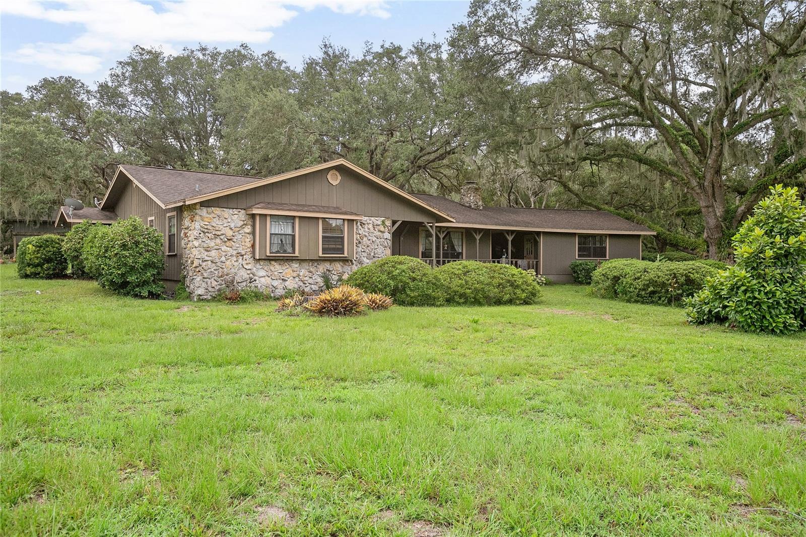 Secluded Country Retreat on 5 Acres in DeLand! Tucked away at the end of a private road, this stunning 3-bedroom, 2.5-bath home offers the serenity of a mountain oasis right in the heart of DeLand. Set on 5 beautifully wooded acres, this unique property blends rustic charm with modern comforts—perfect for those seeking peace, privacy, and space to create. Inside, you'll find a spacious and thoughtfully designed layout featuring: An updated kitchen with granite countertops, custom cabinetry, and stainless-steel appliances, a cozy great room anchored by a gorgeous stone fireplace, separate dining area overlooking a sunken family room—ideal for entertaining, a large master suite with a garden tub, and an inside laundry room for added convenience. Step outside to enjoy the true Florida lifestyle. Relax on the expansive wraparound porch or breezeway as you take in views of native wildlife, including turkeys and deer. Meander through garden walkways shaded by majestic oak trees or simply unwind with your morning coffee or evening drink in complete seclusion. Bonus alert: For hobbyists, entrepreneurs, or those needing extra storage, this property includes a 1,536 sq ft workshop with power and two roll-up doors—offering endless possibilities. Don't miss this rare opportunity to own a one-of-a-kind retreat just minutes from town yet worlds away from the hustle and bustle. Schedule your private tour today—this gem won't last long!
