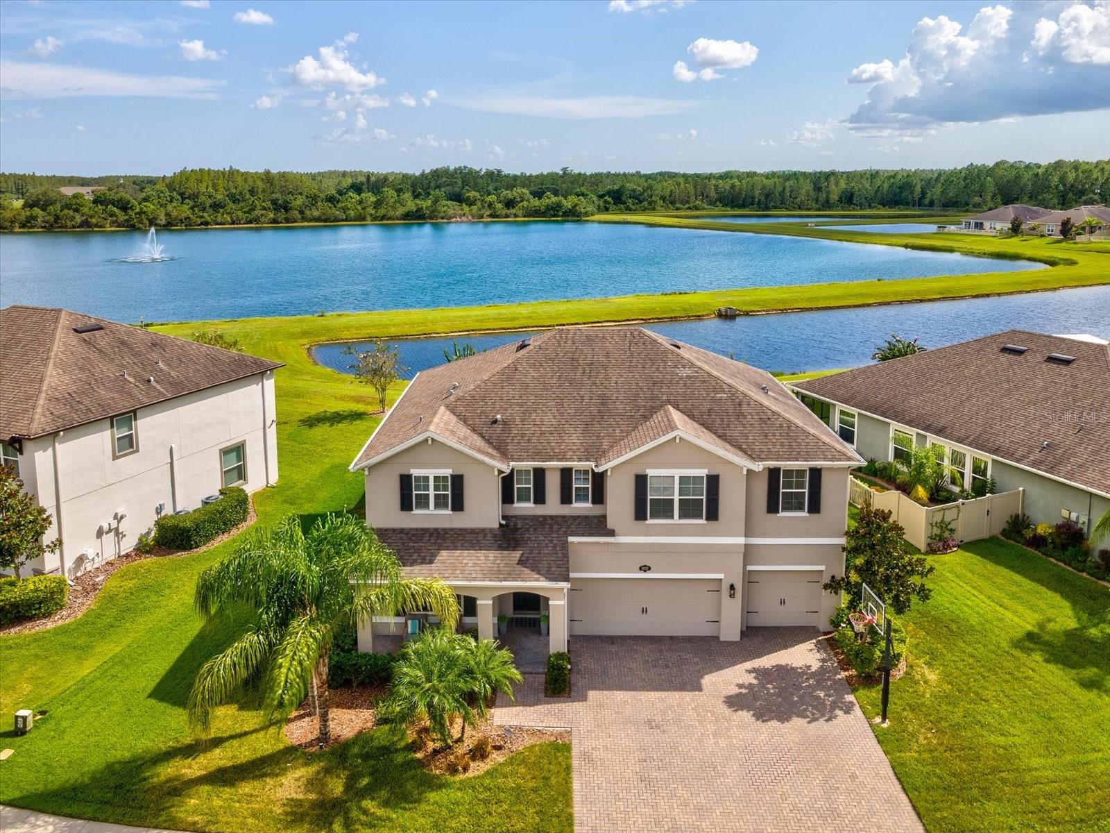 Welcome to this extraordinary 5-bedroom, bonus or flex room, 3.5-bath lakefront and conservation home nestled in the gated enclave of Primrose Estates within Long Lake Ranch in Lutz and zoned for the much anticipated Skybrooke K-8 Pasco County School opening this school year. This maintained 7-year-old residence offers a perfect blend of luxury, functionality, and serene natural beauty, situated on one of the largest lots in the neighborhood with over 10,000 sq ft and breathtaking conservation and lake views. From the moment you arrive, the charming covered front porch and professional landscaping create a warm and inviting curb appeal. Step inside to discover a thoughtfully designed floor plan featuring rich engineered hardwood floors, designer lighting, and custom wood accent walls that add texture and character throughout. The main living area flows seamlessly from the spacious living room to the gourmet kitchen. Highlights include luxury cabinetry with crown molding, tiled backsplash, sleek quartz countertops, a brand new Bosch dishwasher, double wall ovens, a sprawling island perfect for casual meals or entertaining, a butler’s pantry, and a walk-in pantry offering abundant storage. While the kitchen and living area create a natural gathering space, the home also features a dedicated formal dining room—perfect for hosting elegant dinners or holiday celebrations. Natural light pours in through large windows and sliding glass doors, drawing your eye to the peaceful outdoor views and extending the living space to a screened lanai. A flexible first-floor bedroom is ideal for guests or a private office, accompanied by a nearby half bath. Upstairs, retreat to the lavish owner’s suite, a true sanctuary showcasing custom wood ceiling beams, an en-suite spa-like bath with dual vanities, a walk-in shower, and a custom-designed walk-in closet featuring elegant built-in cabinetry. Three additional upstairs bedrooms all include custom-designed walk-in closets, with two sharing a well-appointed Jack and Jill bathroom with dual sinks. An oversized bonus/flex room adds endless possibilities—perfect for a home theater, game room, fitness studio, or homeschool space. The second-floor laundry room adds ultimate convenience and efficiency. Additional standout features include a 3-car garage with built-in storage racks, an electric vehicle charging outlet, and a basketball hoop for outdoor fun. The home also includes hurricane shutters, gutters, four TV wall mounts, pre-wired for speakers in the living area, and beautiful window treatments throughout. This home is part of the vibrant Long Lake Ranch community, offering resort-style amenities such as a pool, tennis and basketball courts, playgrounds, dog park, fishing pier, and scenic walking trails. The expansive backyard provides ample room to design your own custom pool oasis, enhancing the already impressive outdoor living experience. Offering a rare combination of luxury finishes, functional space, and scenic tranquility, this home truly has it all. Don’t miss the opportunity to experience lakefront living at its finest—schedule your private tour today!