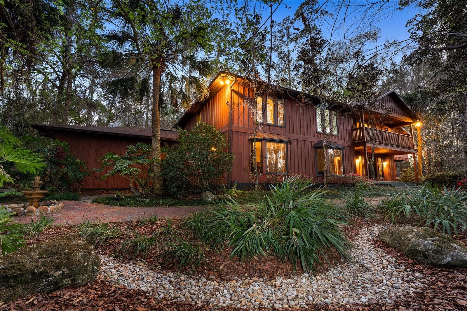 Discover one of Gainesville’s most extraordinary hidden gems — a custom-built John Van Mills pool home tucked away on 2.5+ acres in Shands Woods, less than a mile from the University of Florida. Perched high above protected Hogtown Creek wetlands and surrounded by untouched preserve land, this 6–7 bedroom residence offers exceptional privacy, timeless architecture and a true connection to nature.
Step inside and you’re immediately welcomed by a dramatic two-story great room with cedar batten-and-board walls and a stunning wood-burning Spade stone fireplace that evokes the feeling of a mountain lodge. Walls of windows invite in natural light and frame elevated views of the surrounding preserve — no neighbors in sight.
The main level delivers both comfort and elegance with a formal living room with bay windows, a formal dining room with custom built-ins, and a spacious island kitchen with double ovens, eat-in breakfast area, and French doors that open to the pool — creating an effortless indoor-outdoor lifestyle. The serene primary suite overlooks the pool and wooded backyard and features a spa-style bath with split vanities, walk-in shower, soaking tub, and a unique indoor terrarium.
Upstairs, five additional bedrooms, a large office, and a versatile game room (possible seventh bedroom) provide plenty of room for family, guests and creative work. Two bedrooms include private en suite baths; the others share a large dual-vanity bathroom with jetted tub/shower. A private deck overlooking the pool is accessed from both a bedroom and the game room, while a spiral staircase offers quick access down to the laundry room.
Outside, your private oasis awaits. Enjoy a 30,000-gallon pool surrounded by lush landscaping, total privacy, and your own staircase down to Hogtown Creek. With protected wetlands on the property line and no HOA, this home offers unmatched peace and lifelong seclusion — yet remains just minutes from UF, Shands Hospital, the VA and downtown Gainesville.
Meticulously maintained with a NEW roof (2024), water heaters (2022), fresh interior/exterior paint, and new flooring in most living areas, this home is the perfect blend of classic design and modern convenience.
Looking for space, privacy and a location near UF? This one-of-a-kind Gainesville retreat is truly a must-see— schedule your private tour today.