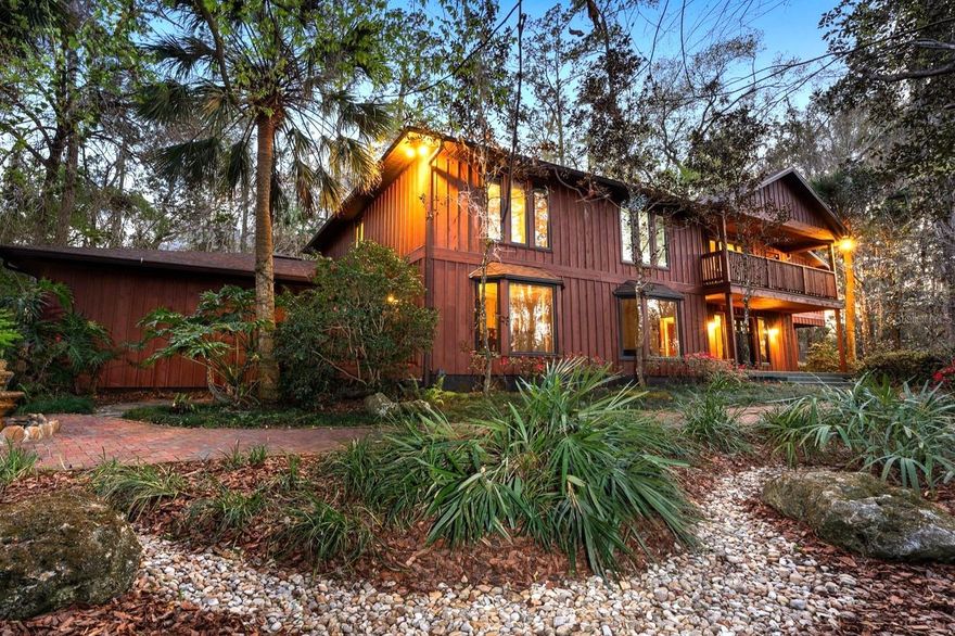 One or more photo(s) has been virtually staged. Tucked away on more than 2.5 acres less than a mile from UF and Shands, this one-of-a-kind property offers the serenity of a nature preserve right in the heart of Gainesville. Perched high above Hogtown Creek, the home captures sweeping, tree-top views and complete privacy — a rare combination of acreage, location, and natural beauty.

Step inside to a dramatic two-story great room wrapped in cedar batten-and-board with a striking Spade stone fireplace that anchors the space and frames the view beyond. Walls of windows blur the line between indoors and out, filling every room with light and a connection to the surrounding preserve. The main level features a formal living room with bay windows, a spacious dining room with custom built-ins, and an island kitchen with double ovens and breakfast area opening to the pool deck.

The primary suite is a peaceful retreat overlooking the pool and wooded backdrop, while upstairs offers five additional bedrooms (two of which have ensuite bathrooms) plus an office and game room — plenty of space for family, guests, or multi-generational living. Recent updates include a NEW 2024 roof, newer water heaters, fresh interior and exterior paint, and luxury vinyl flooring. Outdoors, enjoy the 30,000-gallon pool, multiple decks, and direct access to the creek below.

With timeless design, enduring craftsmanship, and unmatched privacy, this Shands Woods retreat blends the best of nature and convenience — minutes to UF, Shands, the VA, and downtown, yet worlds away from it all.