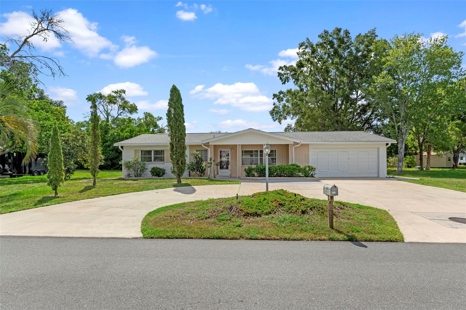 One or more photo(s) has been virtually staged. A home with thoughtful updates and endless possibilities, this property sits on a generous .32-acre home-site with a circular driveway and a welcoming covered front porch, complete with optional access ramp. Built in 1973, it combines solid construction with tasteful upgrades and plenty of room for your personal touch. Step inside to an all-tile interior - even the over-sized two-car garage - for a clean, low-maintenance feel throughout. The large master suite is filled with natural light from double-exposure windows and offers a walk-in closet plus an updated en-suite bath. A spacious second bedroom also enjoys double exposure and is served by an upgraded guest bath with a tub-shower combination. The kitchen is a true highlight, featuring rich wood cabinetry, granite countertops & backsplash, and ample storage and prep space. Just beyond, the enclosed Florida room is brightened by three newer windows (installed in 2022), creating a perfect year-round retreat. For outdoor living, a large paver patio invites gatherings, barbecues, or simply relaxing under the Florida sun. The over-sized garage - fully tiled and equipped with extra space - accommodates both parking and hobbies. A roomy laundry area with a laundry tub adds even more flexibility for storage and organization, while a 12x10 utility shed outside offers additional space for tools, gardening, or recreational gear. With its updated kitchen and baths, durable features, and versatile layout, this home offers the perfect foundation to make it uniquely yours.