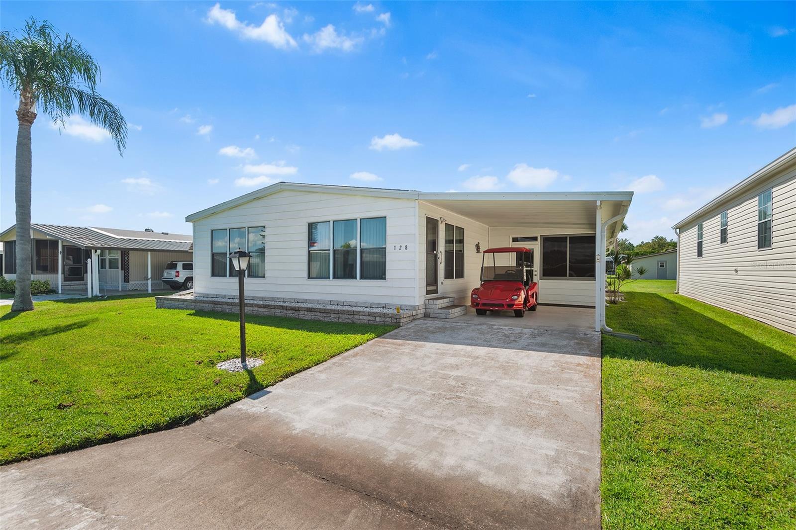Welcome to Orange Manor West in the desirable southeast Winter Haven area. This fully furnished double-wide manufactured home is located in a 55+ gated community. The spacious 2-bedroom, 2-bathroom home offers comfort, functionality, and a host of recent updates. The king-sized primary bedroom features dual walk-in closets and an ensuite bathroom with a new vanity sink installed in 2024. The second bedroom also boasts a closet door and easy access to the second bathroom with updated sink. Stylish new flooring was added in the kitchen, dining area, and both bathrooms in 2020, adding a fresh modern touch.
Enjoy year-round comfort with a 2017 AC/furnace heat pump and a roof replaced the same year. Additional upgrades include a water heater installed in 2023 and a washer/dryer set from 2022. Relax or entertain in the air-conditioned bonus patio, perfect for Florida living. The community offers a wide range of amenities including a heated pool, shuffleboard, horseshoes, bingo nights, putt-putt golf, lake access and more. HOA fees conveniently cover cable, internet, trash, and all community amenities making this home an excellent blend of value and lifestyle in a welcoming active neighborhood.