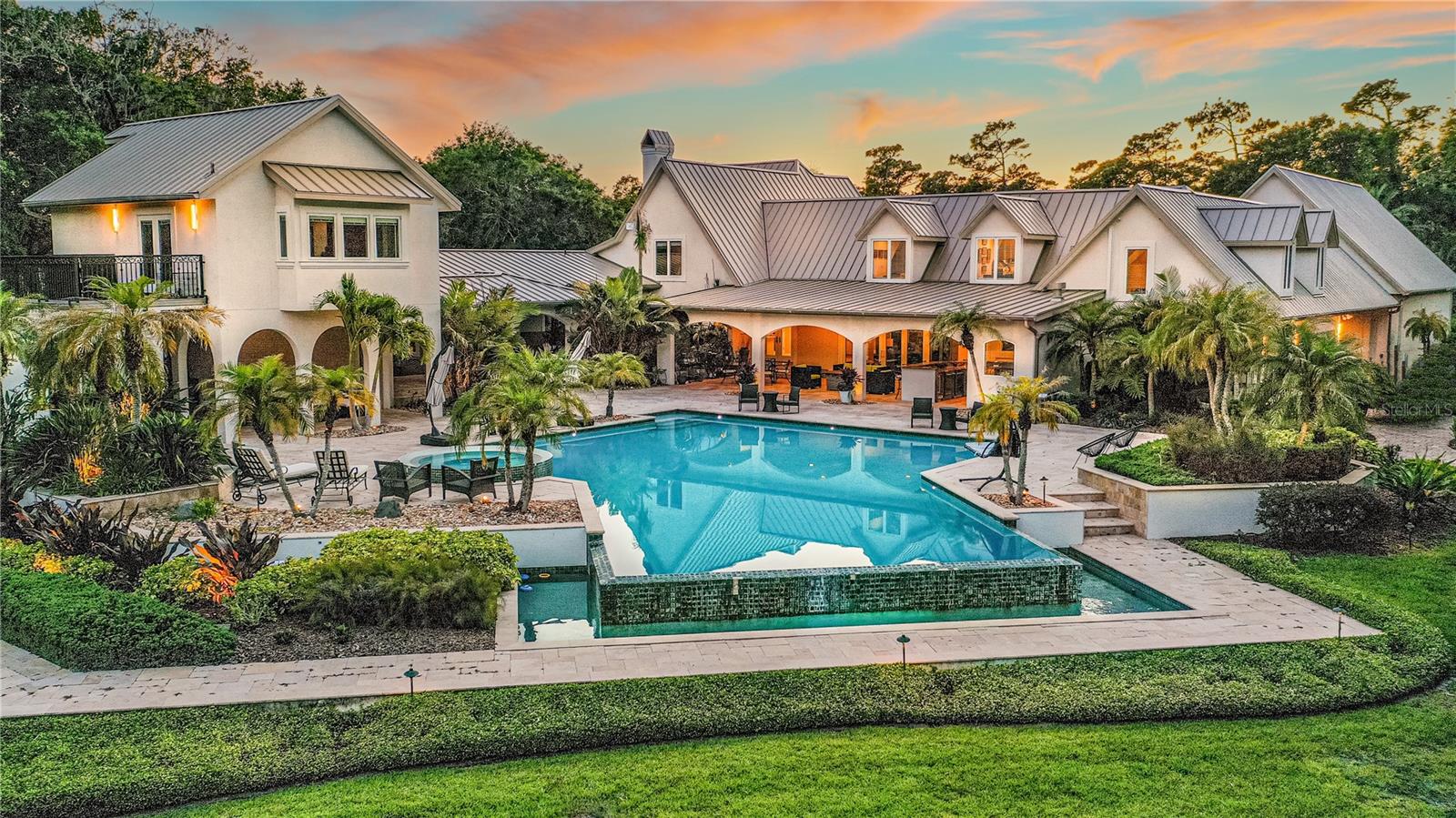 Welcome to this exquisite riverfront estate situated on the Tomoka River in Ormond Beach, Florida. This expansive property spans over 6 acres, offering a private and picturesque setting for those seeking the epitome of waterfront living. With over 8,000 square feet of living space, including a guest house and remarkable features, this estate is a true masterpiece. Let's take a closer look at the stunning details that make this property exceptional.
As you arrive down the paved driveway and enter the motor court, you'll be greeted by a stunning multi-building compound. The architectural elegance extends to the infinity resort-style pool, surrounded by luxurious travertine tiles, creating a serene oasis for relaxation and entertainment. Immerse yourself in the beauty of the water while enjoying the poolside ambiance.
This estate is a car lover's dream with over 2,100 square feet of garage space. The front courtyard features a unique pair of new double garage doors constructed of metal and dark tinted glass, housing an oversized, four-car garage. Through the carport, there is an additional three-car garage providing ample space to house your prized vehicle collection or accommodate guests' vehicles.
Designed with entertainment in mind, this estate offers the perfect setting for hosting grand gatherings. The main home features five bedrooms, providing abundant space for family and guests. Additionally, there are two flexible area rooms that can be customized to suit your lifestyle, whether it be a home office, gym, or media room.
One of the highlights of this property is the fully finished 1,500 square-foot bonus room, located above the four-car garage. With access from the main home or a separate staircase leading to the garage, this versatile space offers endless possibilities. Create your own personal sanctuary, a dedicated entertainment area, or a private retreat to unwind and indulge in your favorite hobbies.
The charming two-story guest house offers a delightful blend of comfort and functionality. The well-designed layout provides flexible living spaces and picturesque views of the river, infinity pool, and park lake grounds. The ground floor of this guest house features a spacious living area/bedroom and bathroom, creating a versatile space for relaxation and rest. The upper level can serve as an office or an additional living area. The built-in cabinetry adds a touch of elegance and offers ample storage space.
The guest house also features a wet bar, creating a perfect setting for entertaining guests and serving refreshments. This versatile space can be tailored to suit your specific needs, whether it's creating a productive work environment or a cozy spot for guests. The highlight of the upper level is undoubtedly the balcony, offering panoramic views of the infinity pool, river, and surrounding grounds.
Meticulously remodeled, this estate leaves no detail overlooked. A full house generator ensures uninterrupted comfort and convenience, providing peace of mind during any power outage. The meticulously manicured grounds are reminiscent of a park, and the boathouse is a standout feature. With two jet ski lifts and a boat lift accommodating boats up to 21 feet, has water, electric, and storage. It's a boater's paradise.
Nestled along the Tomoka River in Ormond Beach, this estate offers the perfect blend of tranquility and accessibility.