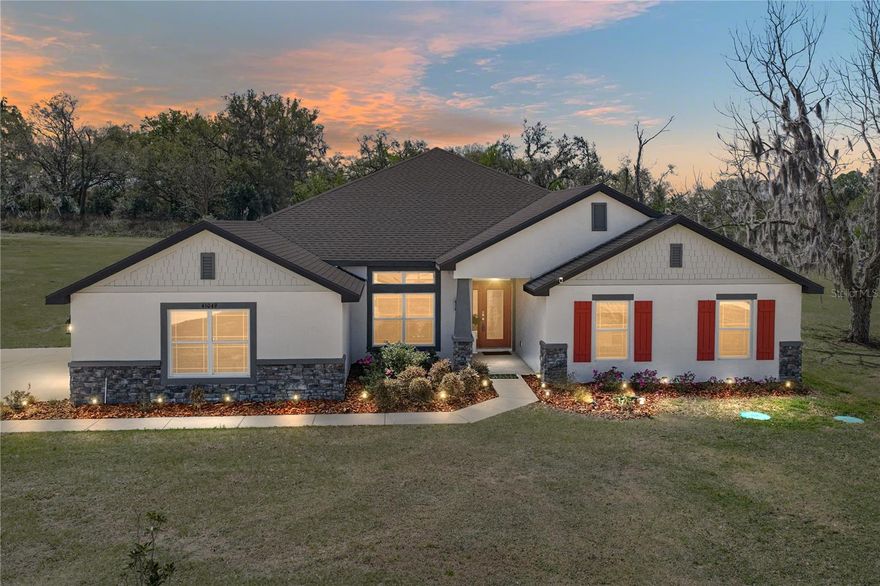 Set on two expansive acres within the gated community of Tara Oaks Plantation, this 2023 built
4 bedroom, 3 bath, 3 car garage home delivers the space, privacy, and sprawling layout that make
acreage living so appealing. A long extended driveway creates a striking approach to the
property, leading to the side facing 3 car garage and a walkway guiding guests to the covered
front entry. The exterior combines attractive landscaping with stone accents and Hardie shake
details, giving the home a refined yet welcoming presence from the moment you arrive. Inside,
soaring vaulted ceilings and tile flooring throughout create a bright, open atmosphere across the
main living areas. Just off the entry, a formal sitting room and dedicated dining space provide
flexibility for hosting gatherings, holiday meals, or creating additional lounge space. The heart of
the home is the impressive 18x20 family room, offering generous space for large furnishings, a
ceiling fan, and direct access to the covered back porch. This room connects comfortably with
the dining area and kitchen while still allowing each space to feel defined. Thoughtfully
positioned just off the main living areas, the eat-in chef’s kitchen provides connection without
being directly exposed to the entire room. Granite countertops offer extensive prep space
alongside a central island, breakfast bar seating, and a full 4 piece stainless steel appliance
package. Storage is a standout feature here with abundant cabinetry and an oversized walk-in
pantry that conveniently connects to the laundry room. The primary suite is impressive in scale
with a spacious 20x17 bedroom, two large walk-in closets, and a well-appointed ensuite
bathroom featuring dual granite topped sinks, a walk-in shower, a separate soaking tub, and a
private water closet. Bedrooms two through four are located down the hall and are all generously
sized, with one featuring its own walk-in closet. Two additional full bathrooms serve this wing of
the home and carry the same finishes and style found throughout the property. Out back, the large
covered porch overlooks a wide open backyard framed by a wooded backdrop, creating a
peaceful setting with plenty of room to add a pool, garden, or simply enjoy the surrounding
acreage. Tara Oaks Plantation offers the rare combination of gated privacy and large homesites,
all while being conveniently positioned between Dade City and Lakeland with easy access to US
98 for shopping, dining, and local conveniences. If you have been searching for a newer
construction home with acreage, generous living space, and a tranquil gated setting, this property
is well worth a closer look. Schedule your private showing today!