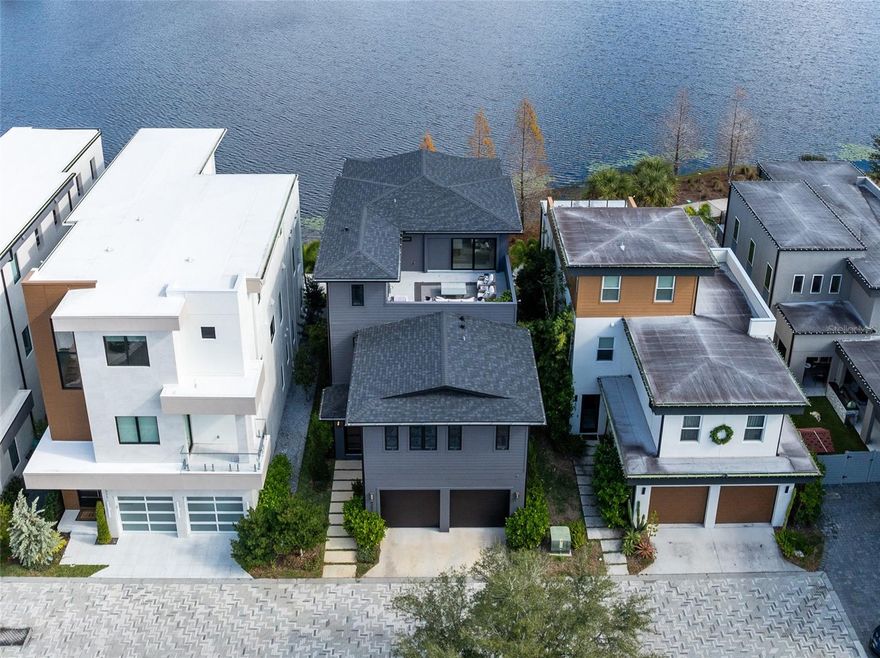 Amazing three story lakefront home where you can enjoy both morning sunrises and evening sunsets from the front porch and multiple balconies.

This stunning residence offers a rare blend of modern design, flexible living spaces, and seamless indoor outdoor living across three thoughtfully designed levels. From the moment you arrive, clean architectural lines and a welcoming entry create a striking first impression.

The first floor opens to a stylish foyer leading into a spacious family room filled with natural light. This level features three generously sized bedrooms, including one currently used as a home office, offering excellent flexibility for guests, multigenerational living, or remote work. A full bathroom completes this level with a layout designed for comfort and functionality.

The second floor serves as the heart of the home with an expansive open concept living area ideal for entertaining and everyday living. Walls of windows create a bright and airy atmosphere throughout. The kitchen anchors the space with sleek cabinetry, custom refrigerator panels that blend seamlessly with the design, modern finishes, and ample prep and storage space. The kitchen flows effortlessly into the dining and living areas, while large glass doors open to a covered balcony overlooking the lake. From here, enjoy peaceful morning sunrises and stunning evening sunsets with water views as your backdrop.

Tucked away on this level, the primary suite offers a private retreat featuring a spacious bedroom, a custom walk in closet, and a spa style bathroom with dual vanities, a freestanding soaking tub, and an oversized glass enclosed shower with multiple shower heads.

The third floor is a true showpiece, featuring a spacious media and entertainment room that opens to both a rooftop balcony and an additional terrace. This level is perfect for hosting, movie nights, or simply relaxing while taking in sweeping lake views and unforgettable sunsets. The elevated outdoor terrace provide a private retreat rarely found in modern homes, offering multiple areas to lounge, dine, grill, unwind, watch the game  or look at the stars at night. 

Throughout the home, thoughtful details, designer finishes, and abundant natural light enhance the modern aesthetic while maintaining warmth and livability. With multiple living areas, flexible bedroom options, and exceptional outdoor spaces on every level, this lakefront home delivers an elevated yet effortless lifestyle in a truly special setting.