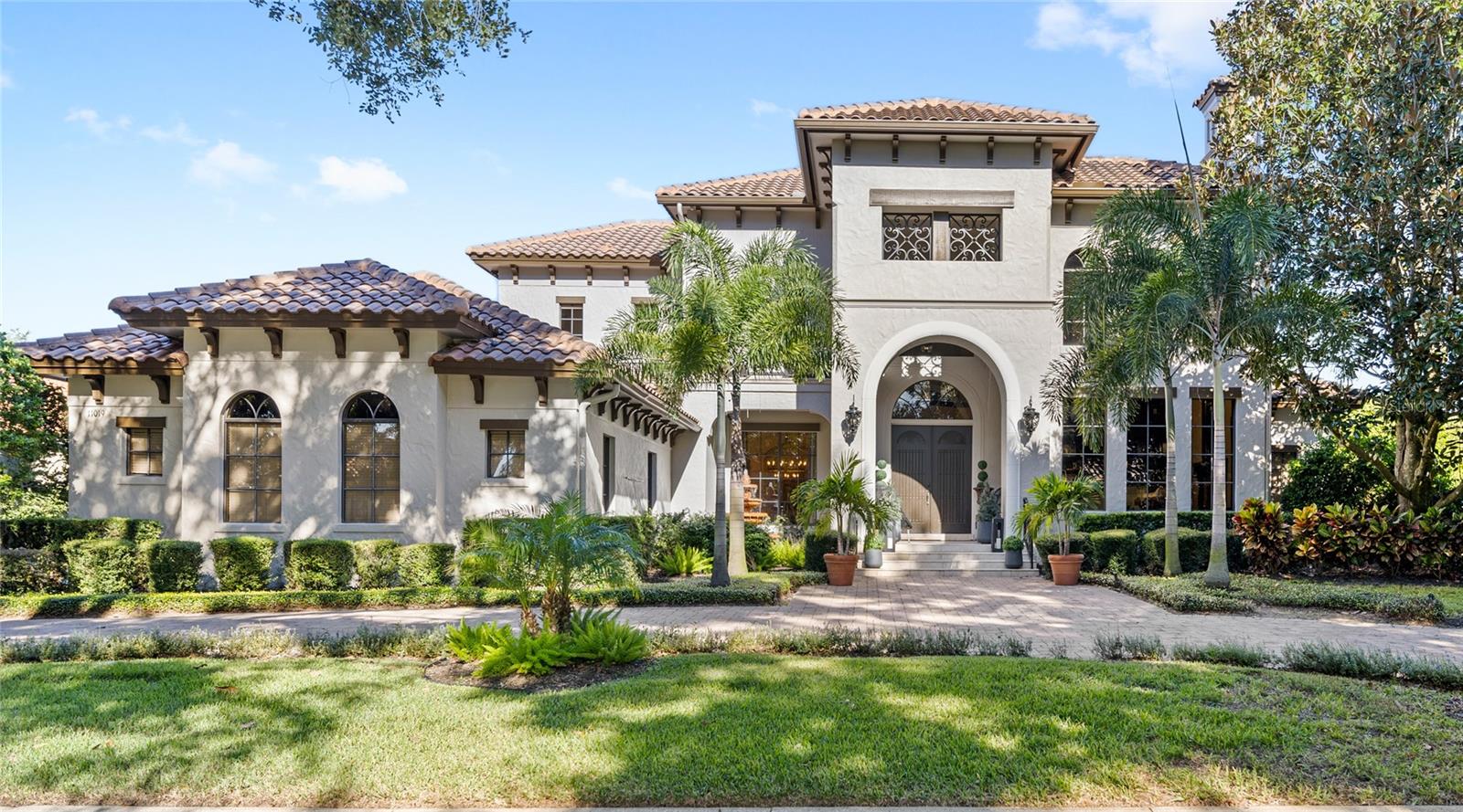 Welcome to 11019 Ullswater Drive, a timeless Italian-inspired residence built by Brierhill Custom Homes. Set on over half an acre within the 24-hour manned gates of The Reserve at Lake Butler Sound, this home offers exceptional updates, modern amenities, and a thoughtfully designed floor plan.
The impressive brick paver circular driveway leads to a grand front entry. Stepping through the arched French doors, you’ll immediately notice the attention to detail, including: custom travertine inlays, elegant ceiling work, and expansive views of the pool and backyard entertaining space.
The chef’s kitchen features Z-Line appliances, refaced cabinetry in a modern color palette, a large pantry, updated lighting, and ample counter space. Overlooking the spacious family room, this area is perfect for gathering and entertaining. The family room features panoramic pool views through large windows and French doors, along with a fireplace, custom solid-wood built-ins, and coffered ceilings.
Adjacent to the family room, the first-floor media room and parlor provide additional space for entertaining, complete with a full wet bar, sliding glass doors to the lanai, and direct access to the guest bathroom.
The primary suite, located in a private wing of the home, offers a floor-to-ceiling windows, impressive accents like a tray ceiling, and lanai access. The en-suite bath includes dual vanities, a soaking tub, a walk-in shower, and a custom walk-in closet system.
Also on the first floor is a study with soaring ceilings, built-ins, and a floor-to-ceiling fireplace, overlooking the front of the home. A formal living room, dining room with butler’s pantry pass-through, dedicated laundry room, and three-car garage are also accessible on the first floor. A first-floor guest suite with an updated en-suite bathroom completes the main level.
Upstairs, you’ll find a spacious loft with balcony access, three large guest bedrooms, and two full baths.
The outdoor living space is equally as impressive as the interior of the home, featuring a screened and covered lanai with seating and a summer kitchen, overlooking a private pool, spa, cabana, and putting green. The landscaping is newly upgraded and low-maintenance, featuring turf throughout. At night, the entire space features up lighting, creating additional ambiance throughout the rear yard.
Throughout the home, thoughtful craftsmanship and modern updates complement the classic European design, creating a balance of warmth and sophistication rarely found in many homes available today.
Located in one of Windermere’s most sought-after communities, this home offers privacy, beauty, and proximity to downtown Windermere, Restaurant Row, and Walt Disney World. Request a full copy of the upgrades and features list for this home. Schedule your private tour today.